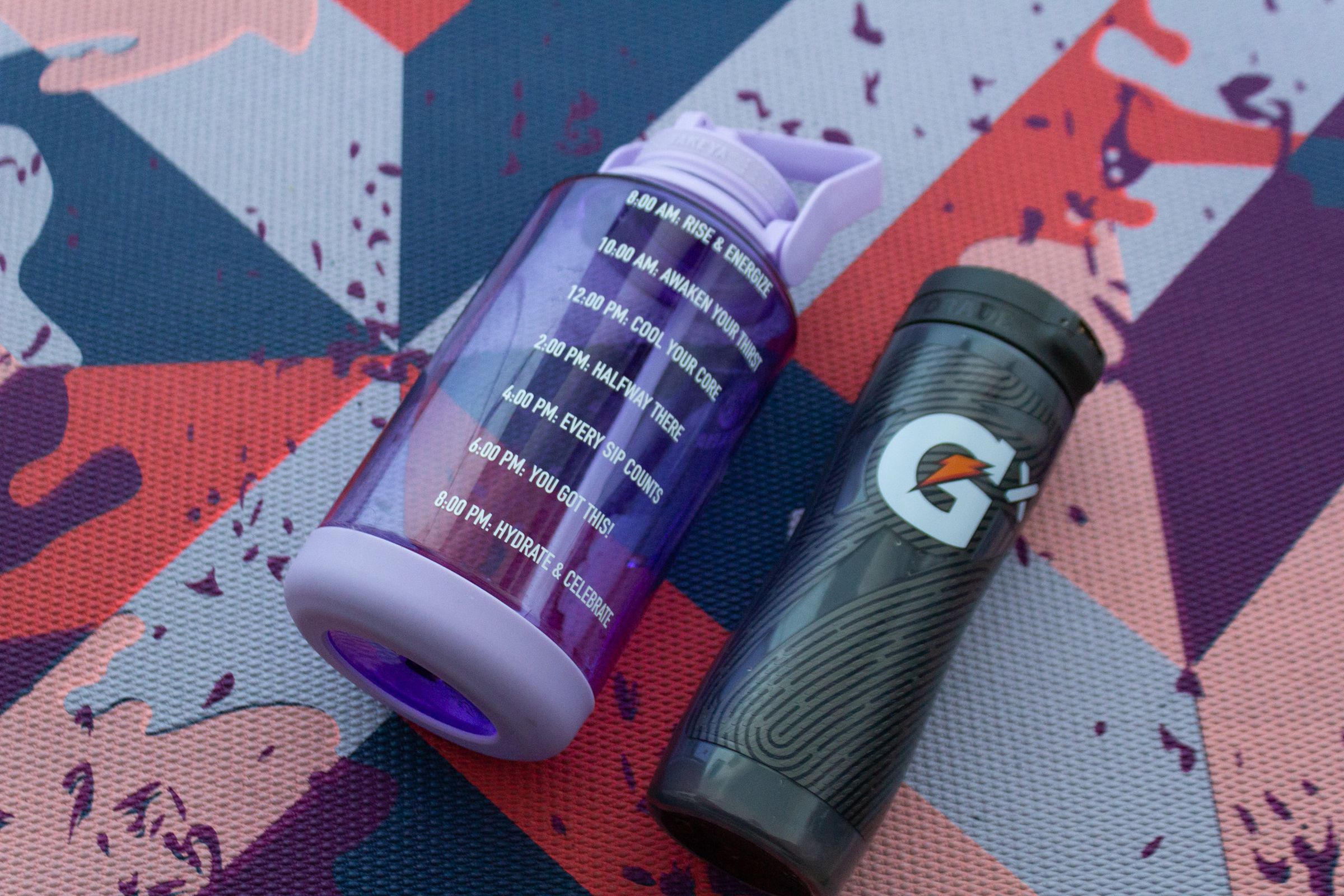 Large purple water bottle with hourly markers next to Gatorade Smart Gx bottle  