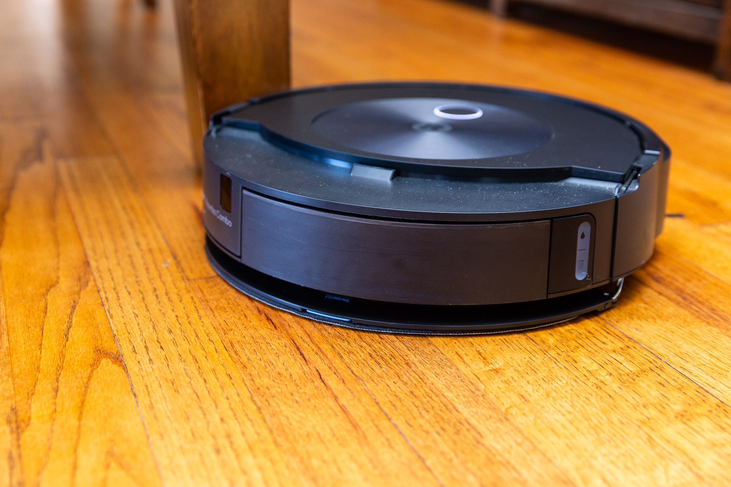 A robot vacuum with mopping arm deployed. The arm is a circular section of the top case of the Roomba with a mop pad on the underside. It presses against the floor when in use.