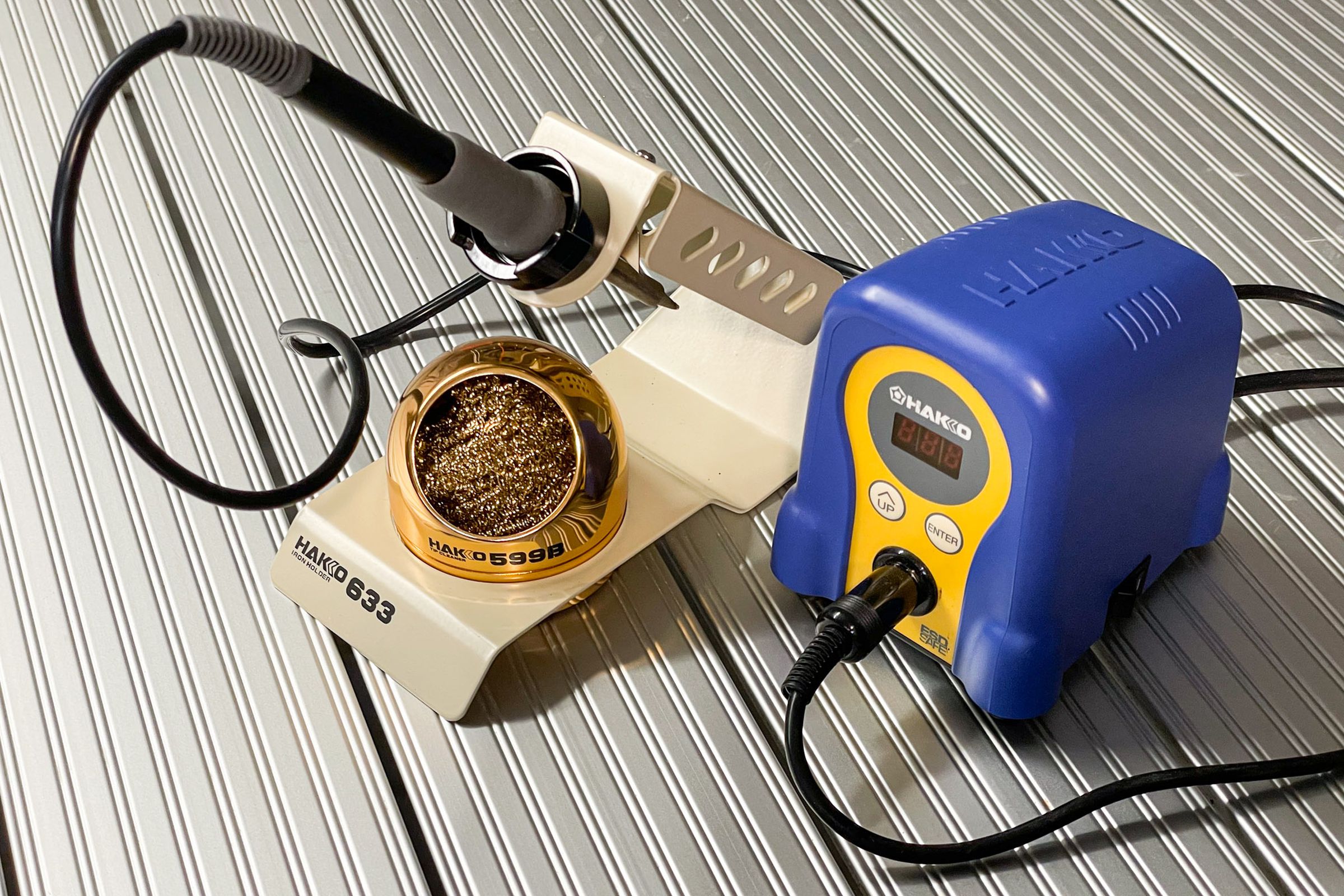A picture of a Hakko brand soldering iron and a tan Hakko Iron holder.