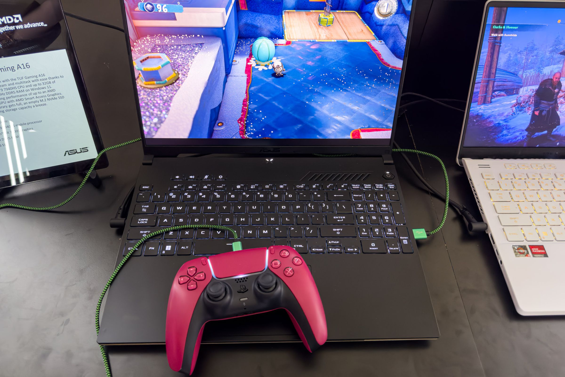El teclado Asus TUF Gaming A16 visto desde arriba con un controlador PS5 rojo apoyado en el panel táctil.