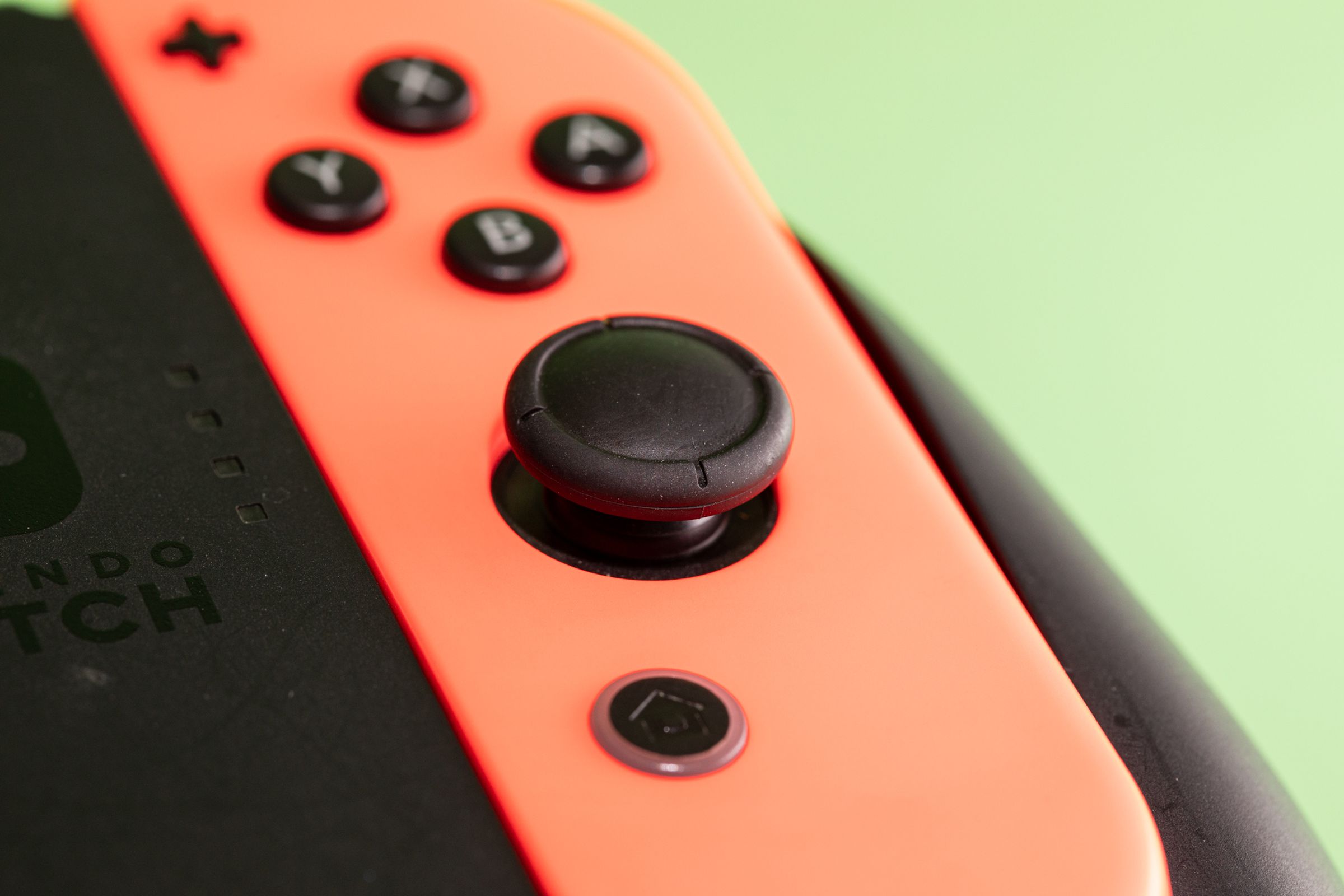 A black low-profile Nintendo Switch joystick embedded in a red controller.