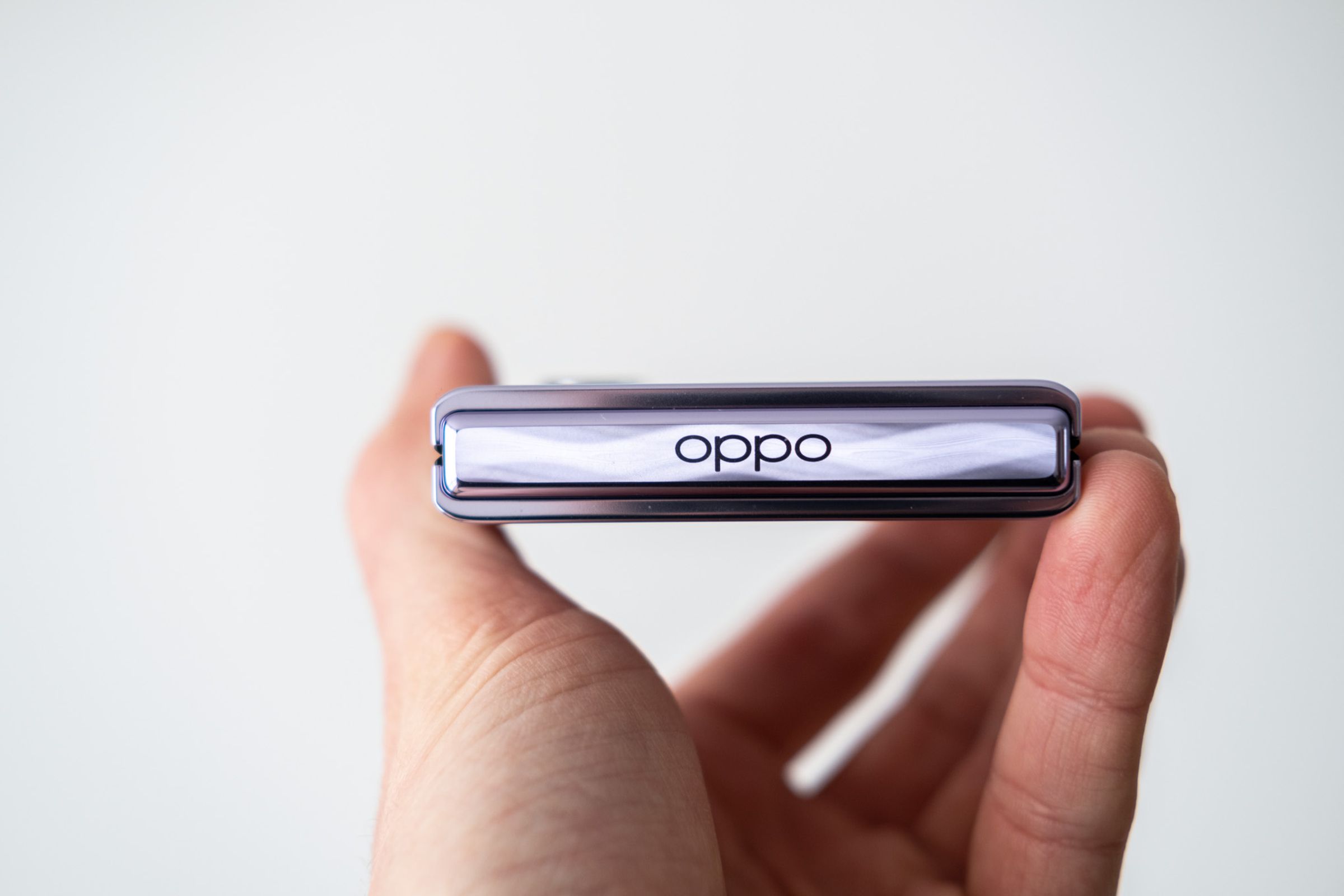 hand holding Oppo find n2 flip in profile view showing glossy finish and Oppo text etching