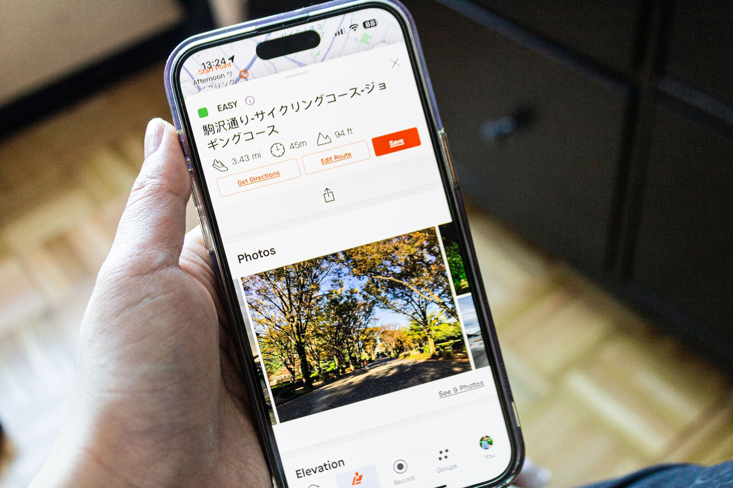 Person holding iPhone showing the new Strava Recommended Routes photo feature with a route in Tokyo.