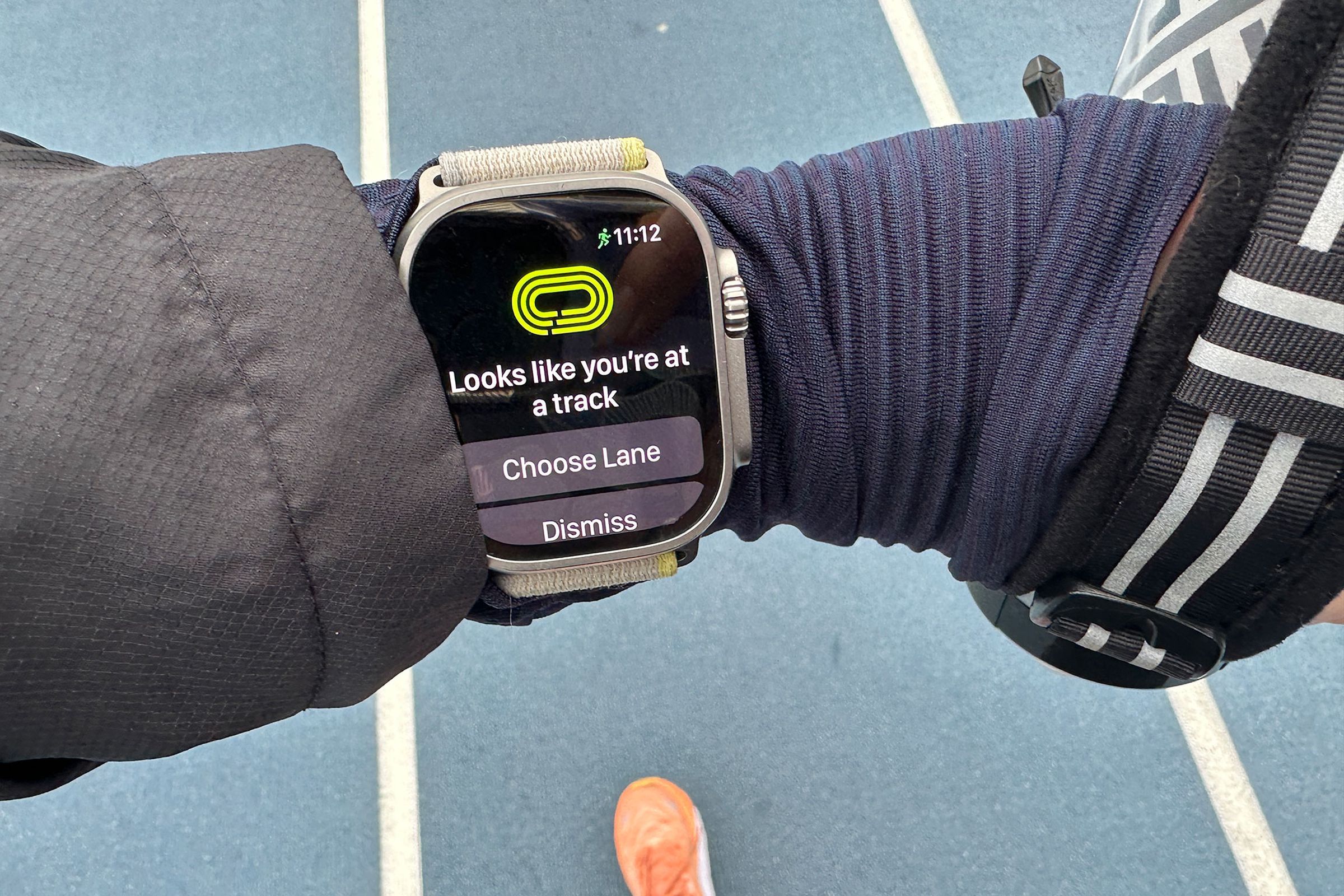 Apple Watch Ultra on wrist prompting user to pick a lane after arriving at a running track.