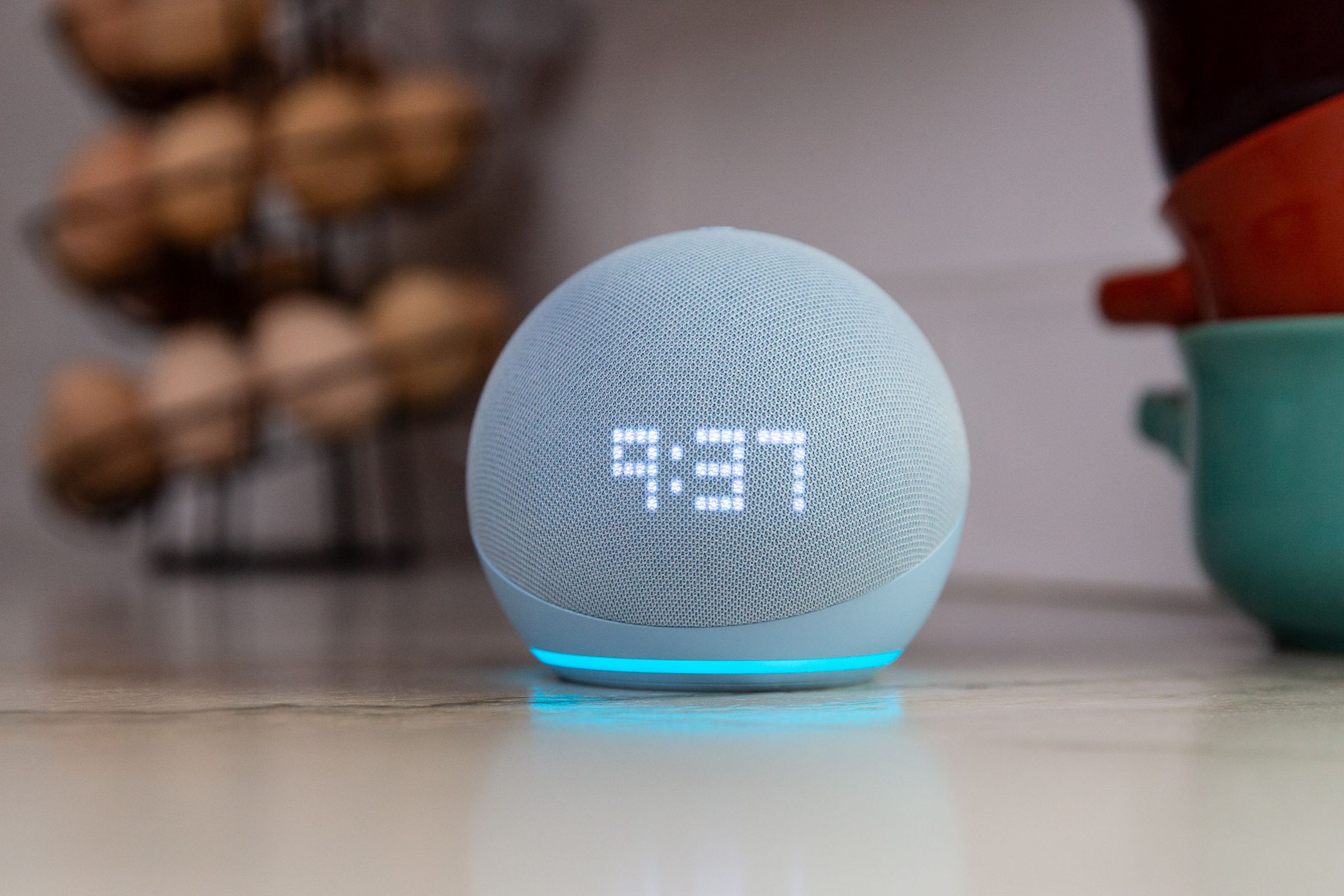 Amazon’s fifth-gen Echo Dot smart speaker showing the time on its display while sitting on a kitchen counter.