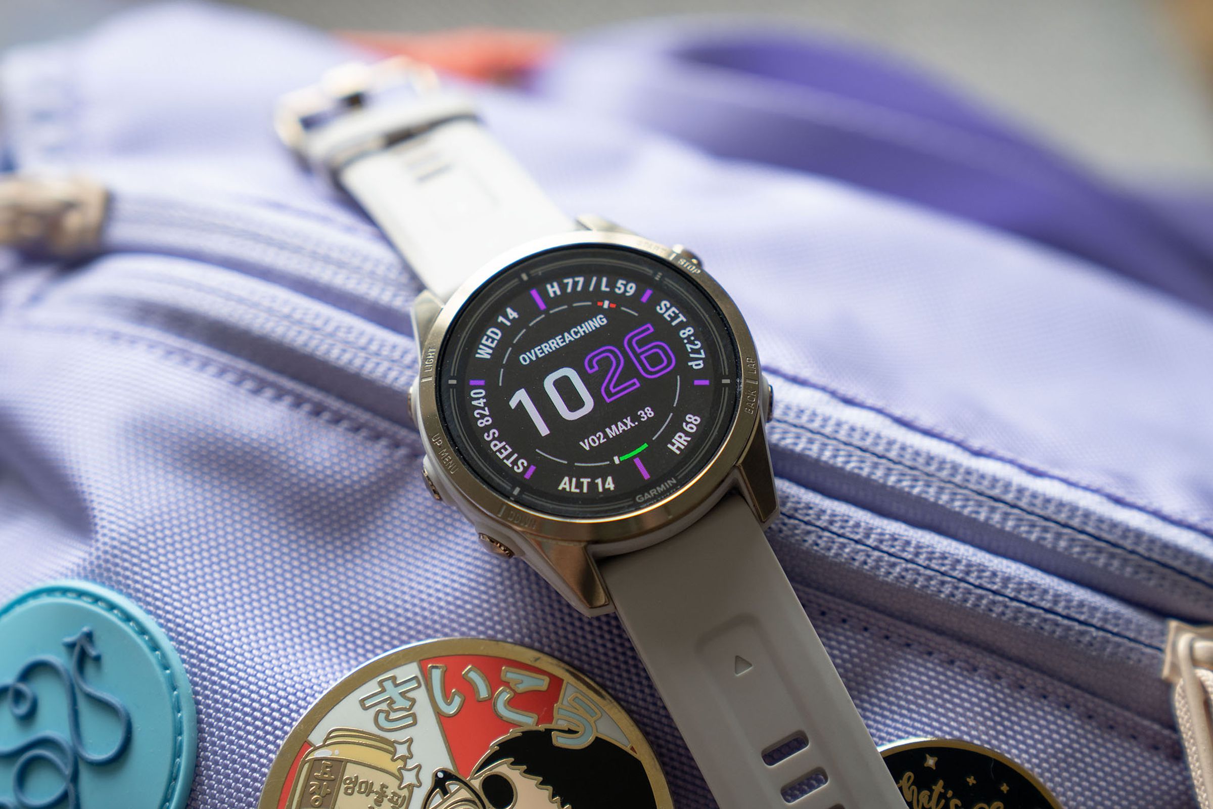 The 42mm Garmin Epix 2 Pro on top of a lavender bag with enamel pins.