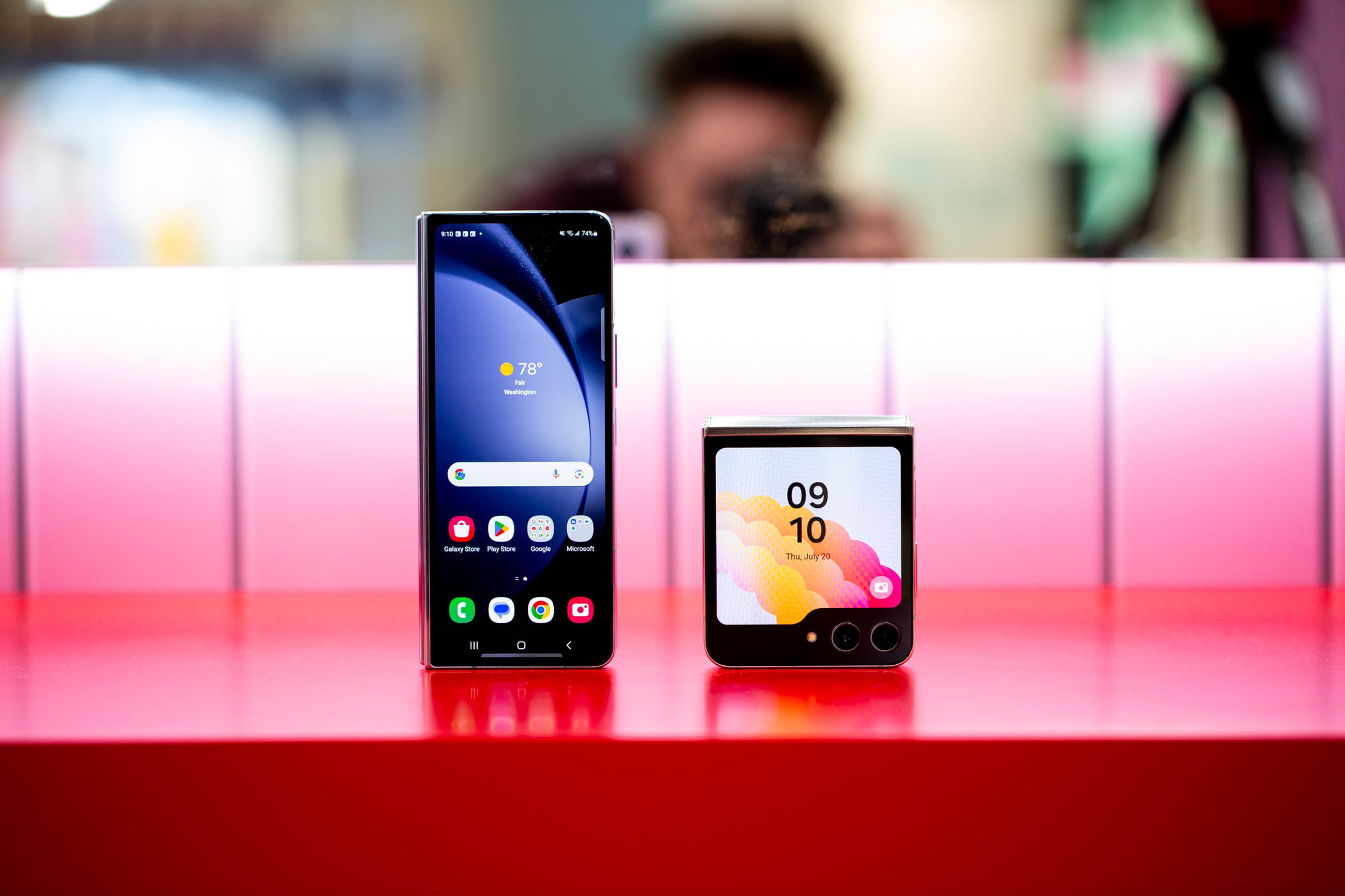 The Samsung Galaxy Z Fold 5 and Z Flip 5, standing side by side in their folded positions on a red table.
