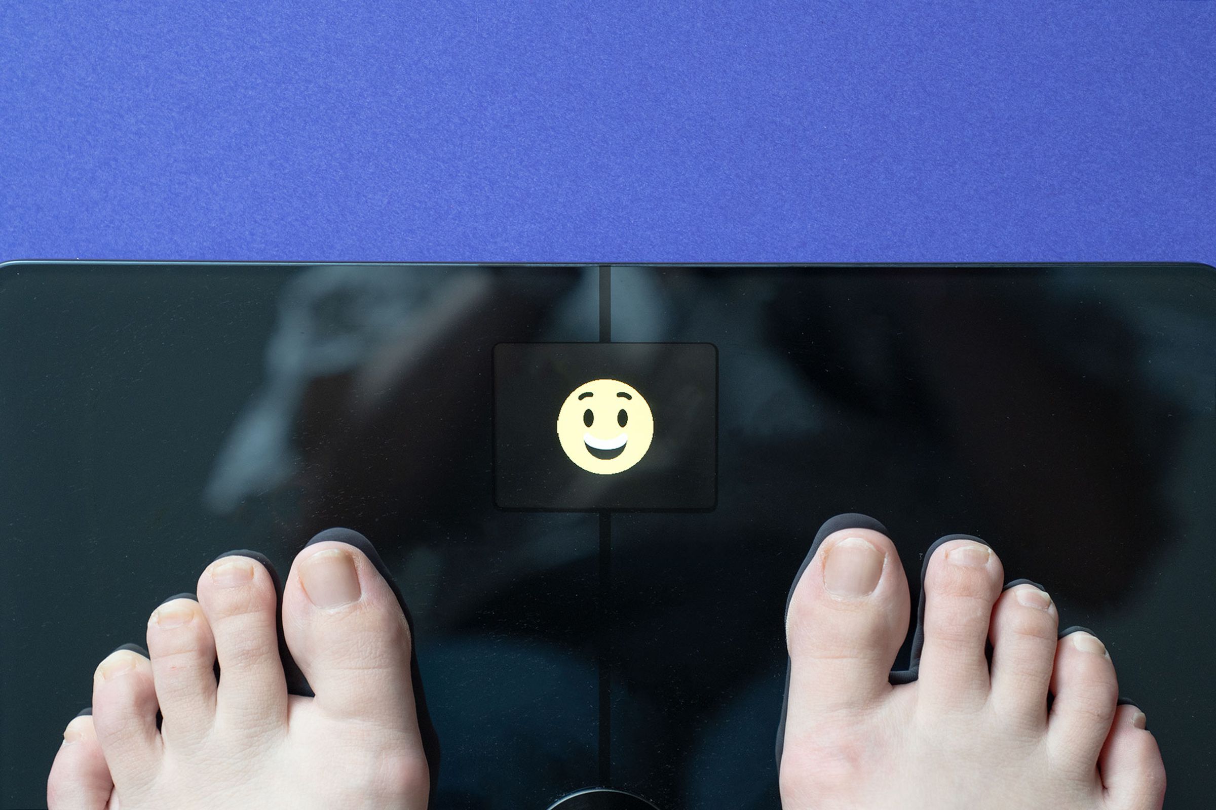 Person standing on scale with smiley face showing in LED display
