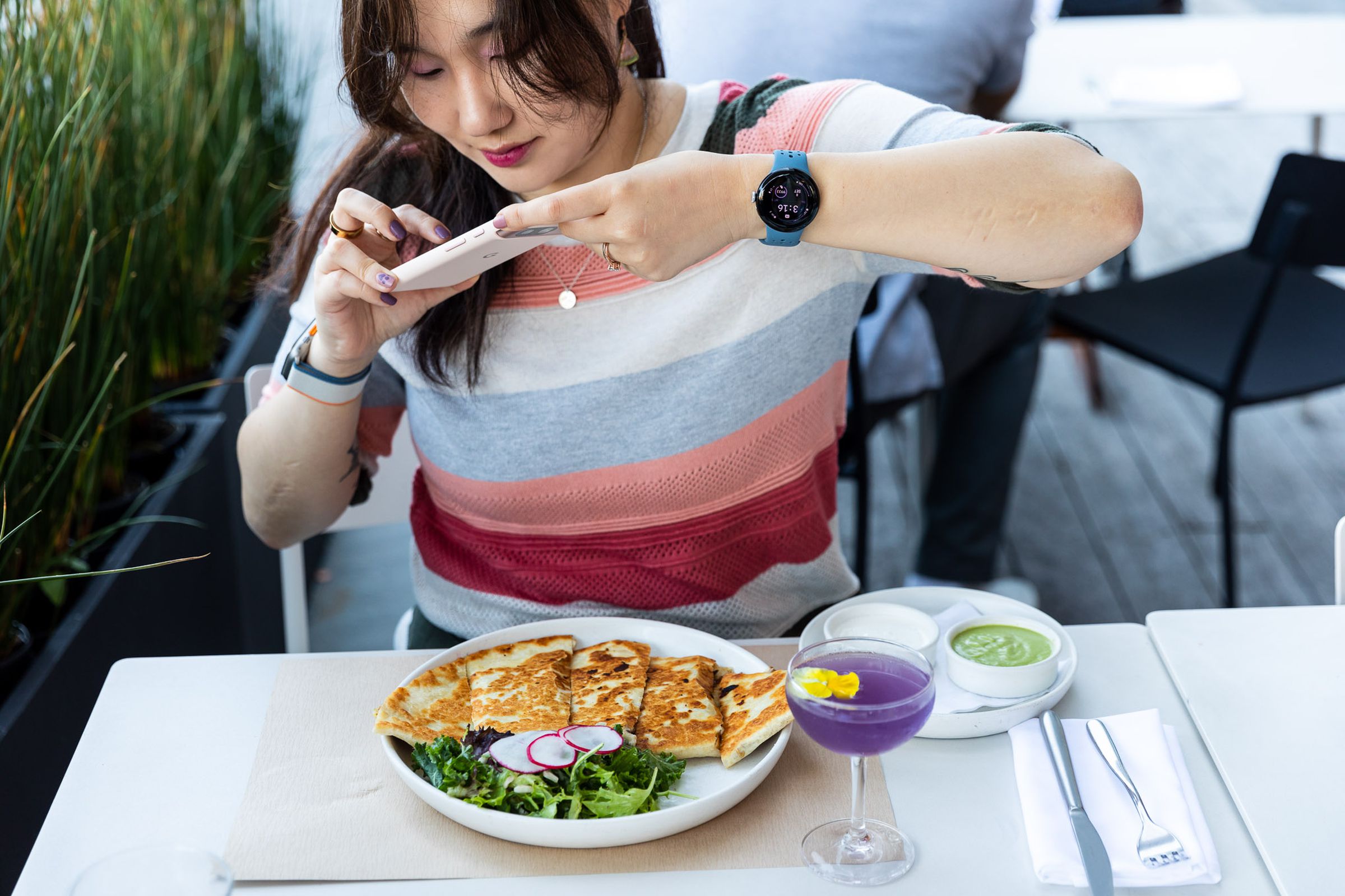 Person taking picture of food with Pixel 8 while wearing Pixel Watch 2.