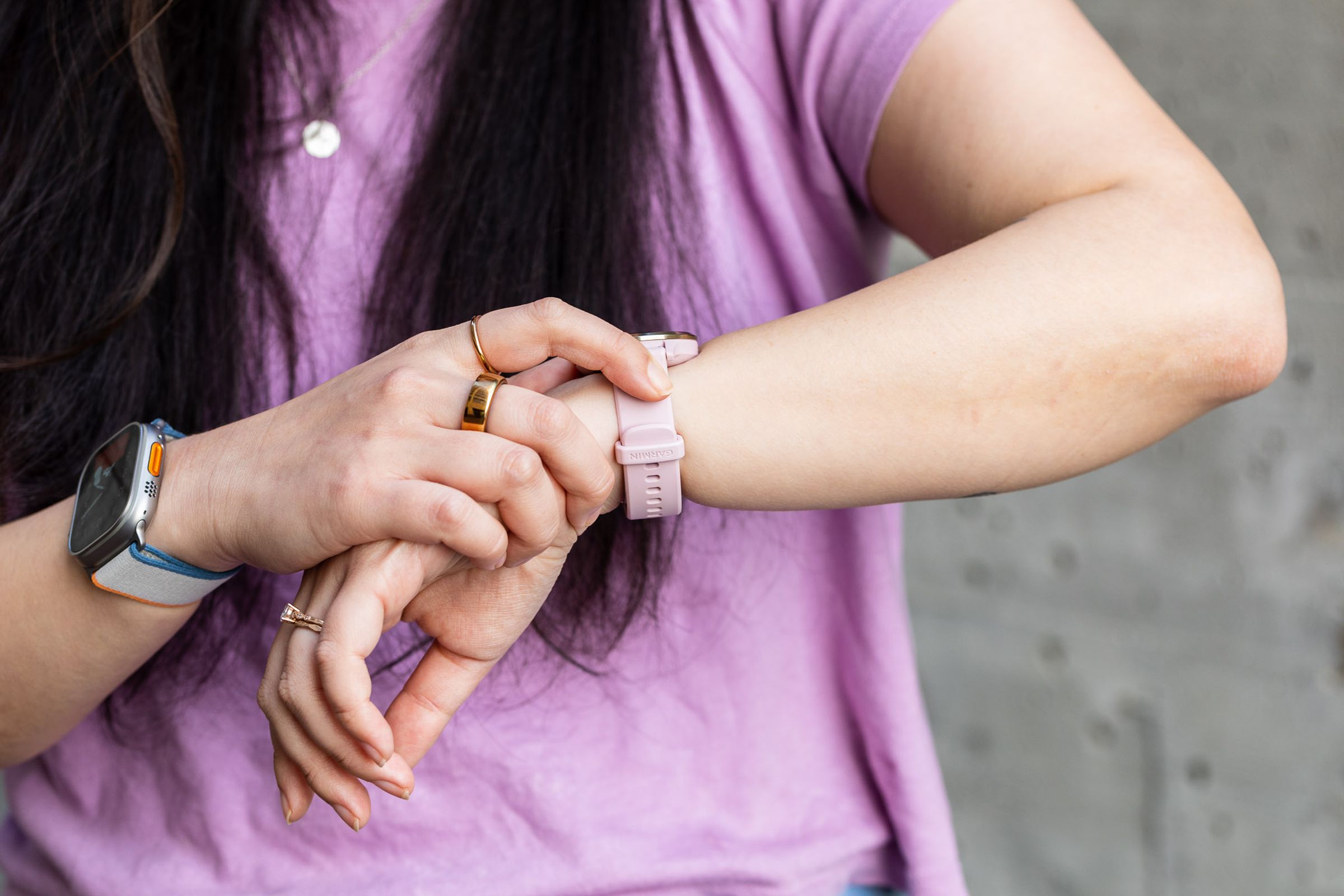 Person in purple shirt looking at pinkish purple Venu 3 on her wrist.
