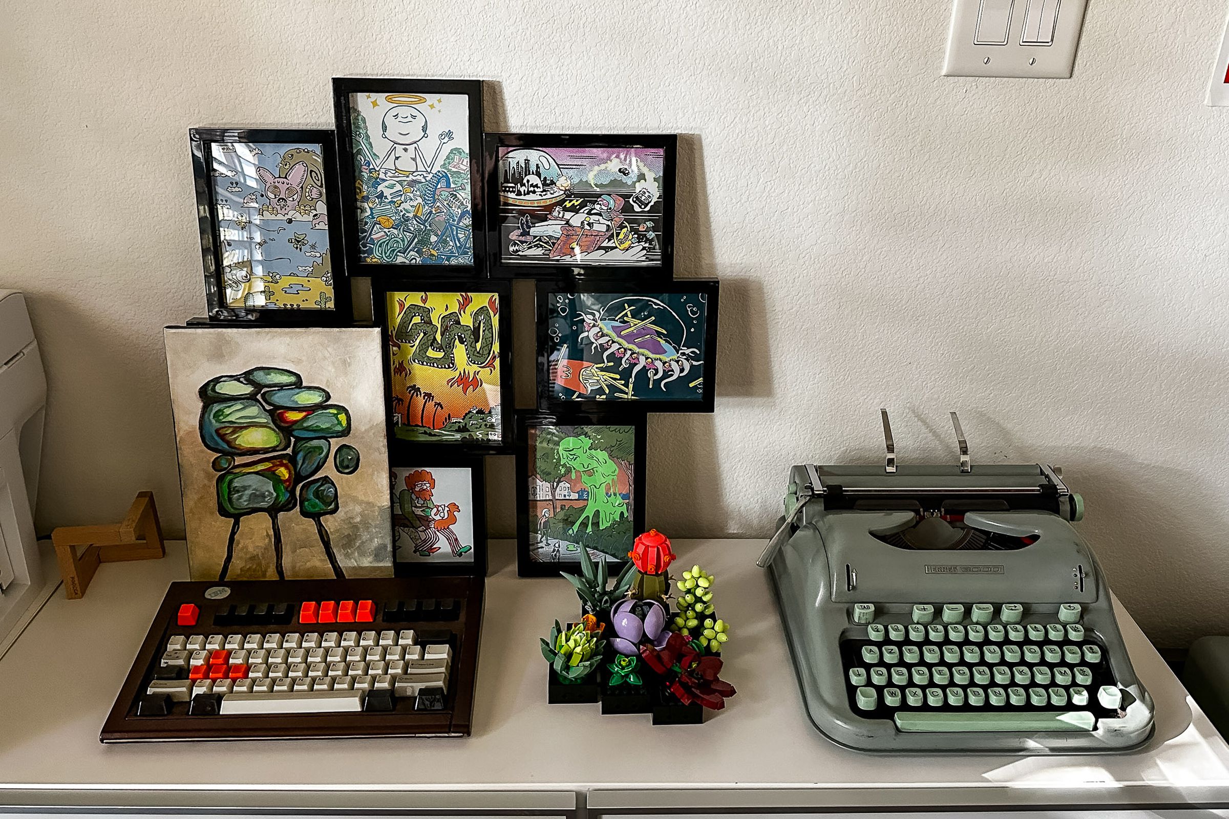 Table with art, a keyboard on the left, and a typewriter on the right.