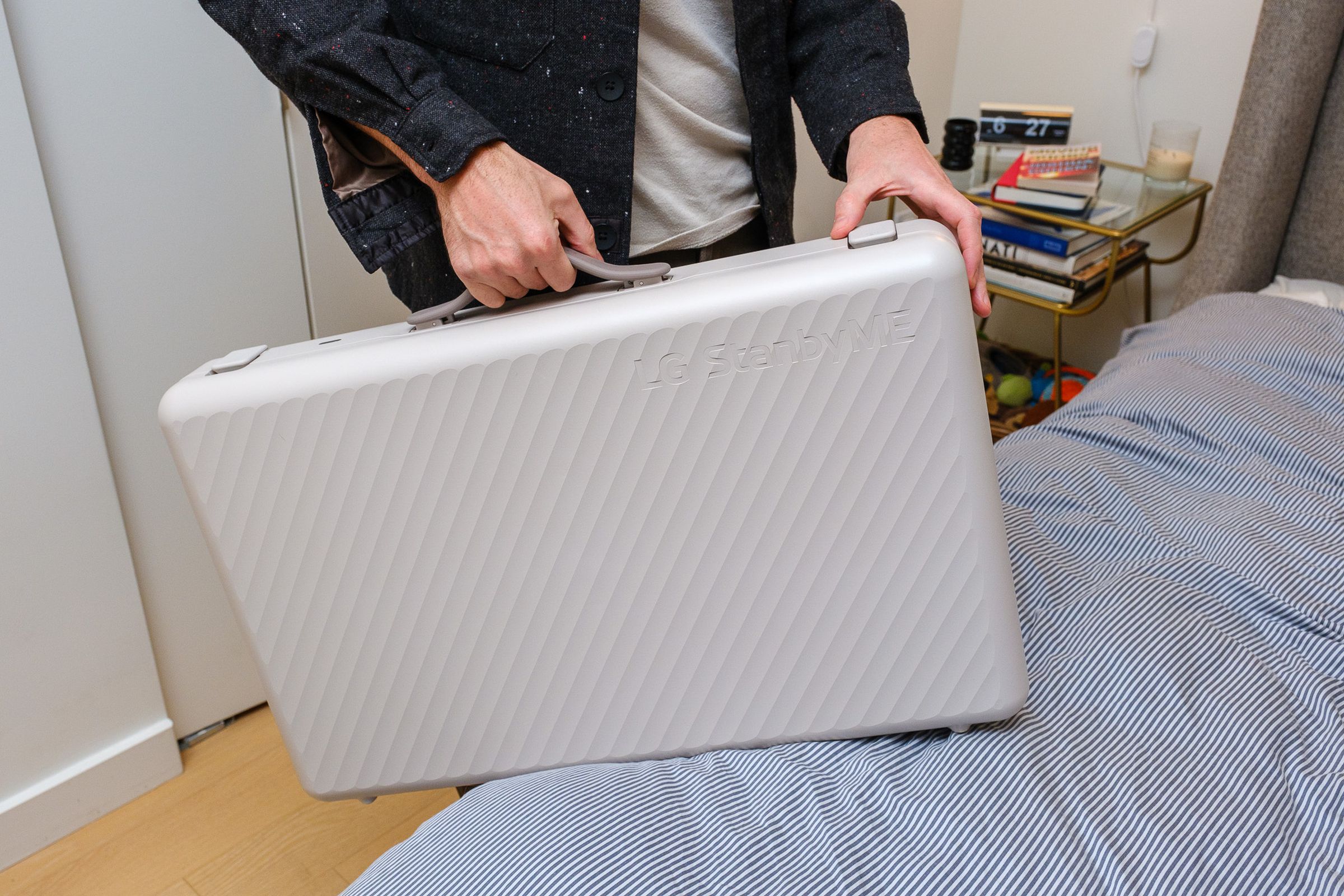 A photo of a man holding LG’s StanbyME Go briefcase TV.