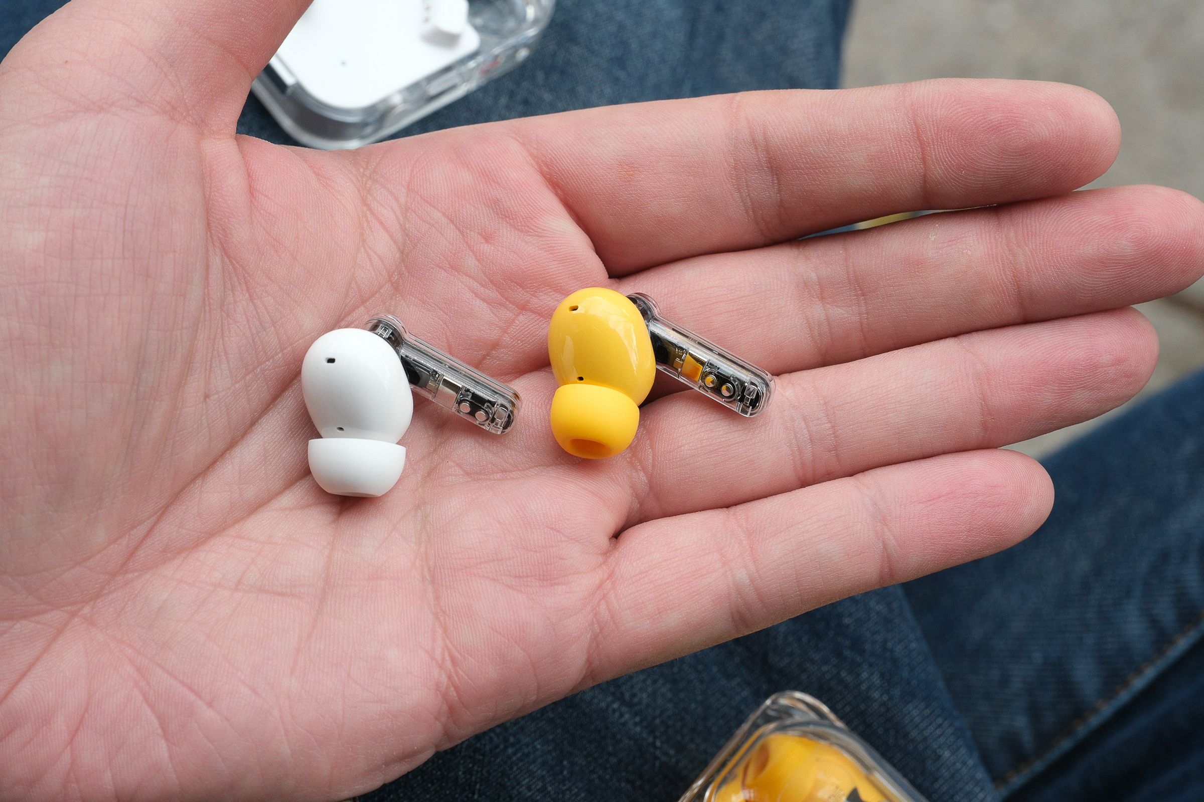 A photo of Nothing’s Ear and Ear (a) earbuds side by side in someone’s palm.