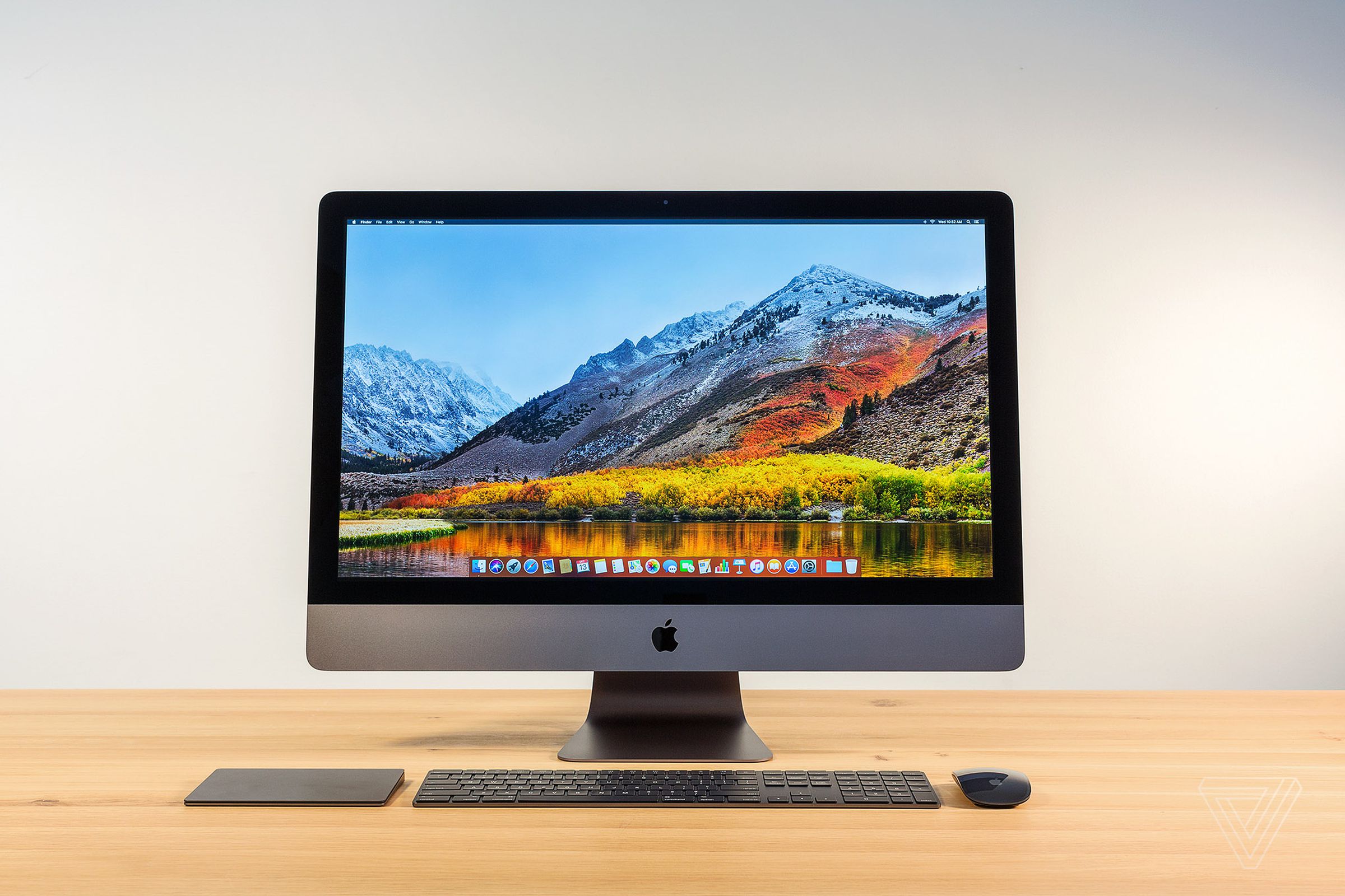 An iMac Pro on a wooden desk with matching keyboard, mouse, and trackpad.
