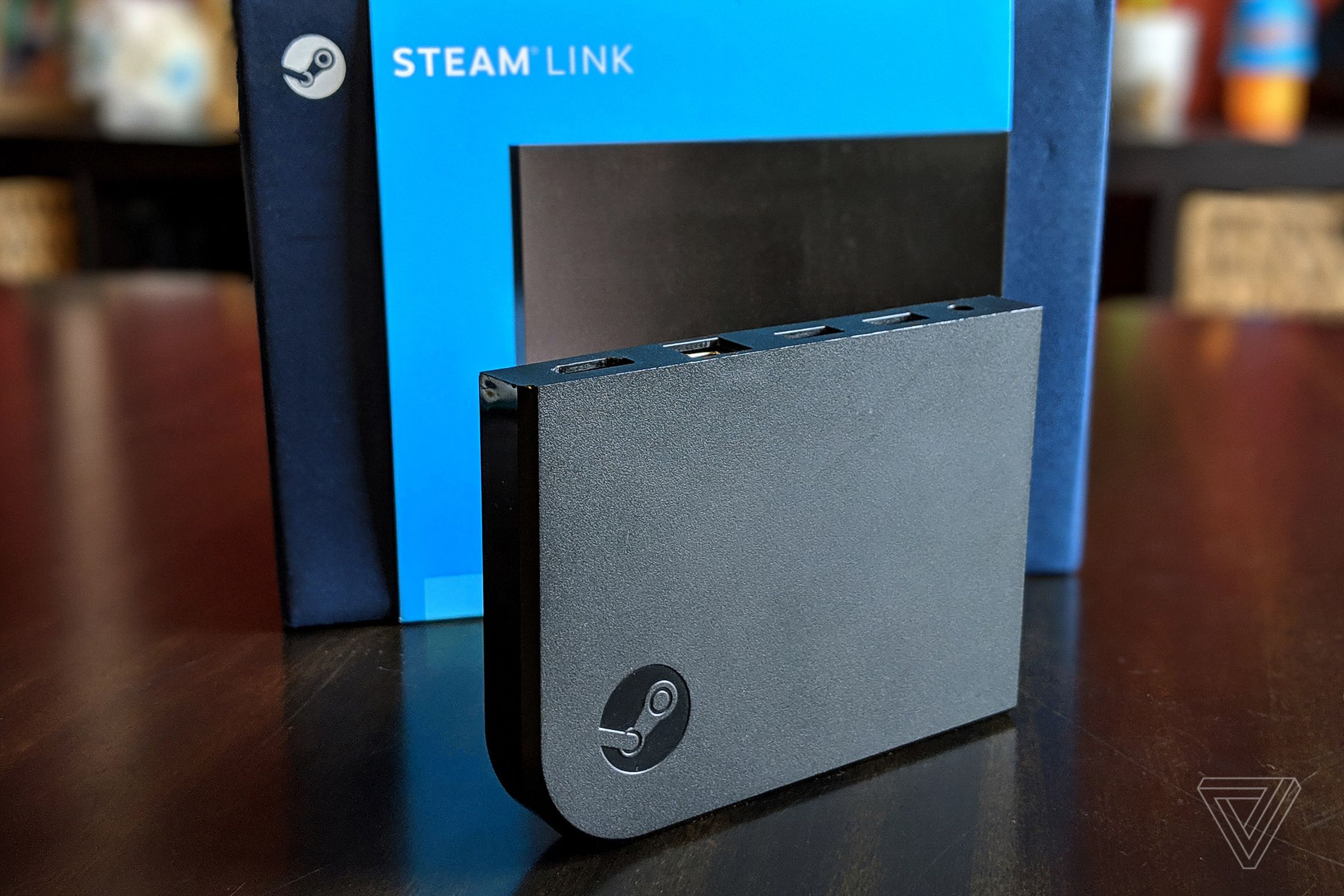 A photograph of a Steam Link besides its packaging on a wooden table.