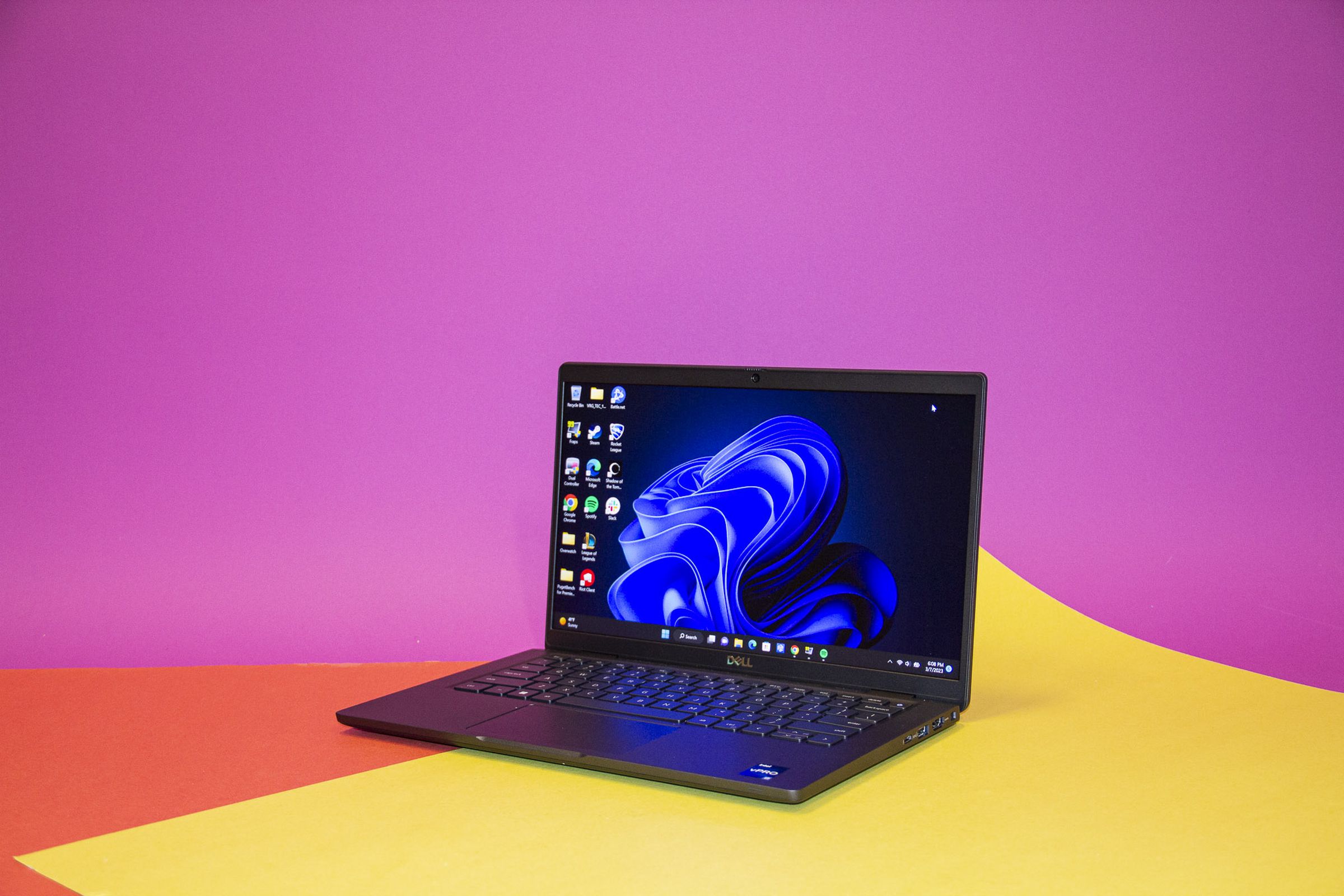 The Dell Latitude 7330 on a yellow and pink background open and angled to the left.