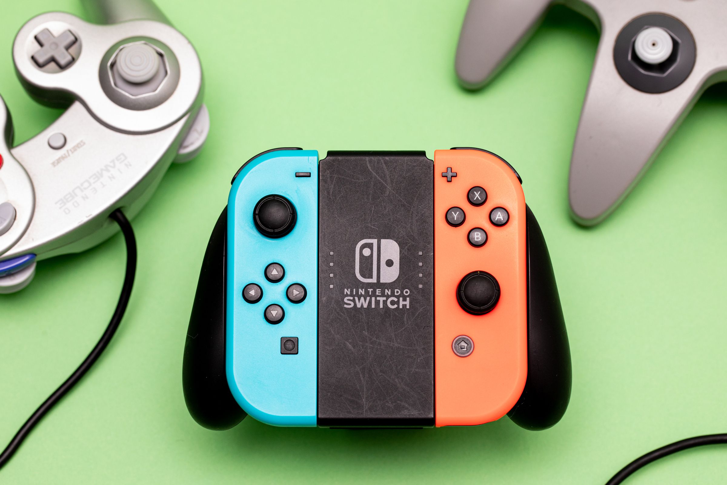 Image of Joy-Cons in a grip on a light green background surrounded by an N64 and GameCube controller.