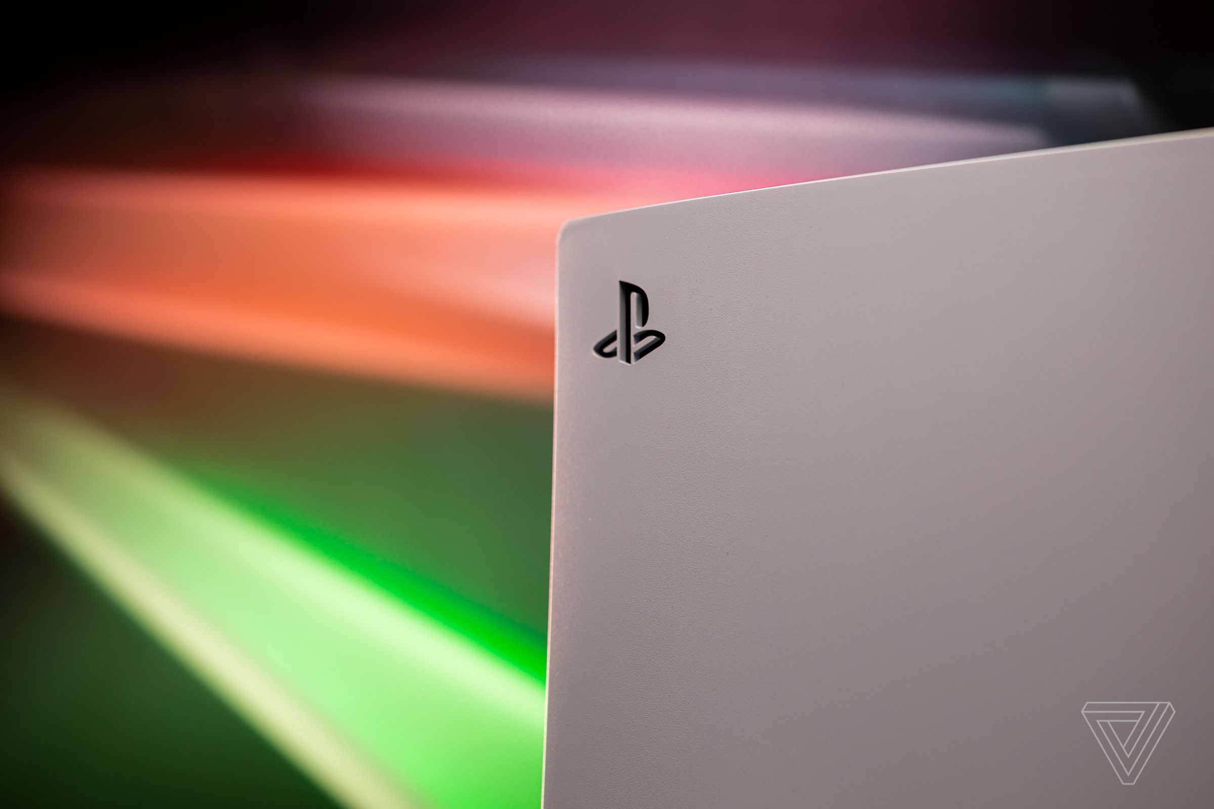 A close-up of the PlayStation 5’s side, with streaking colored lights in the background.