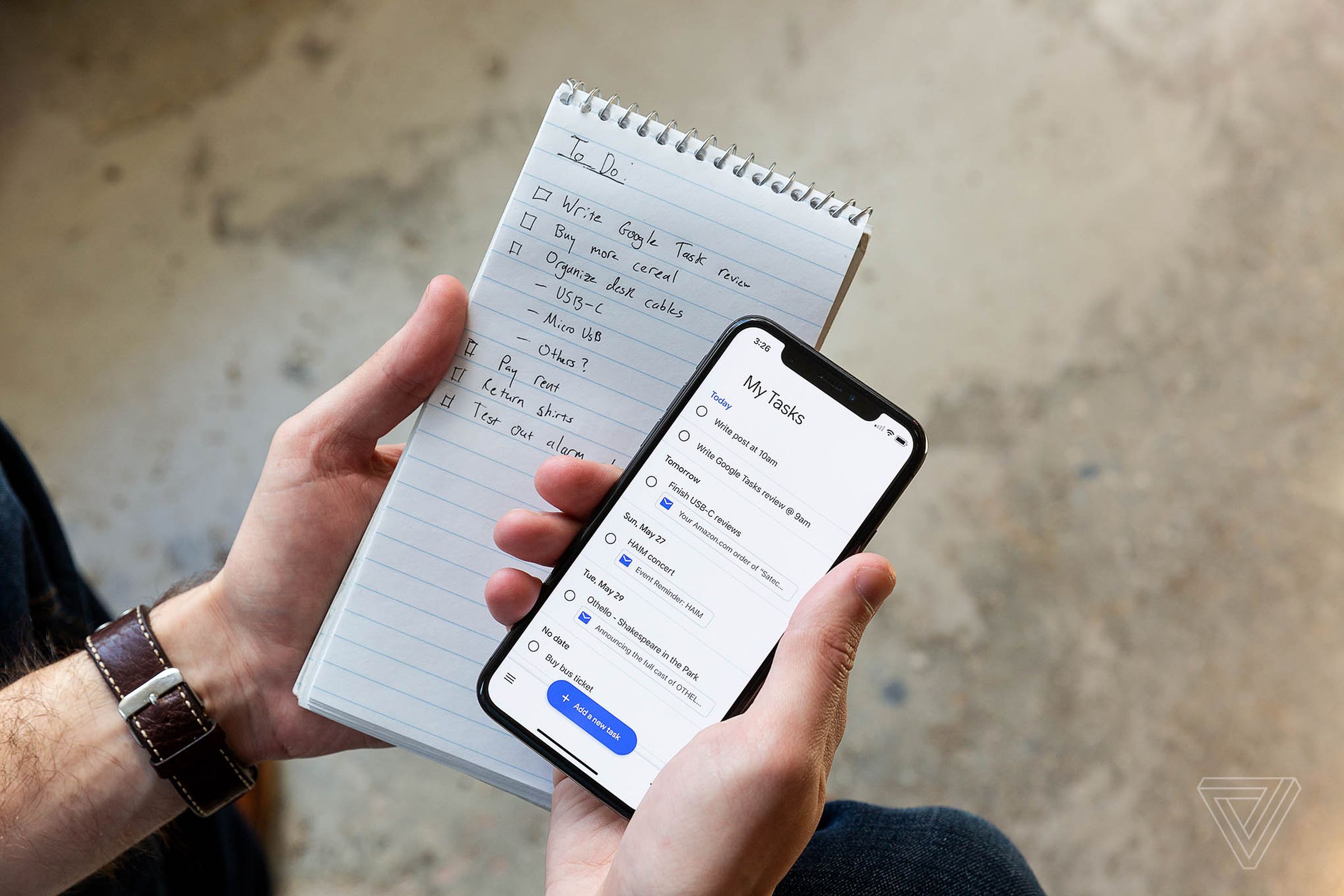 A person holding an iPhone and a paper to-do list.