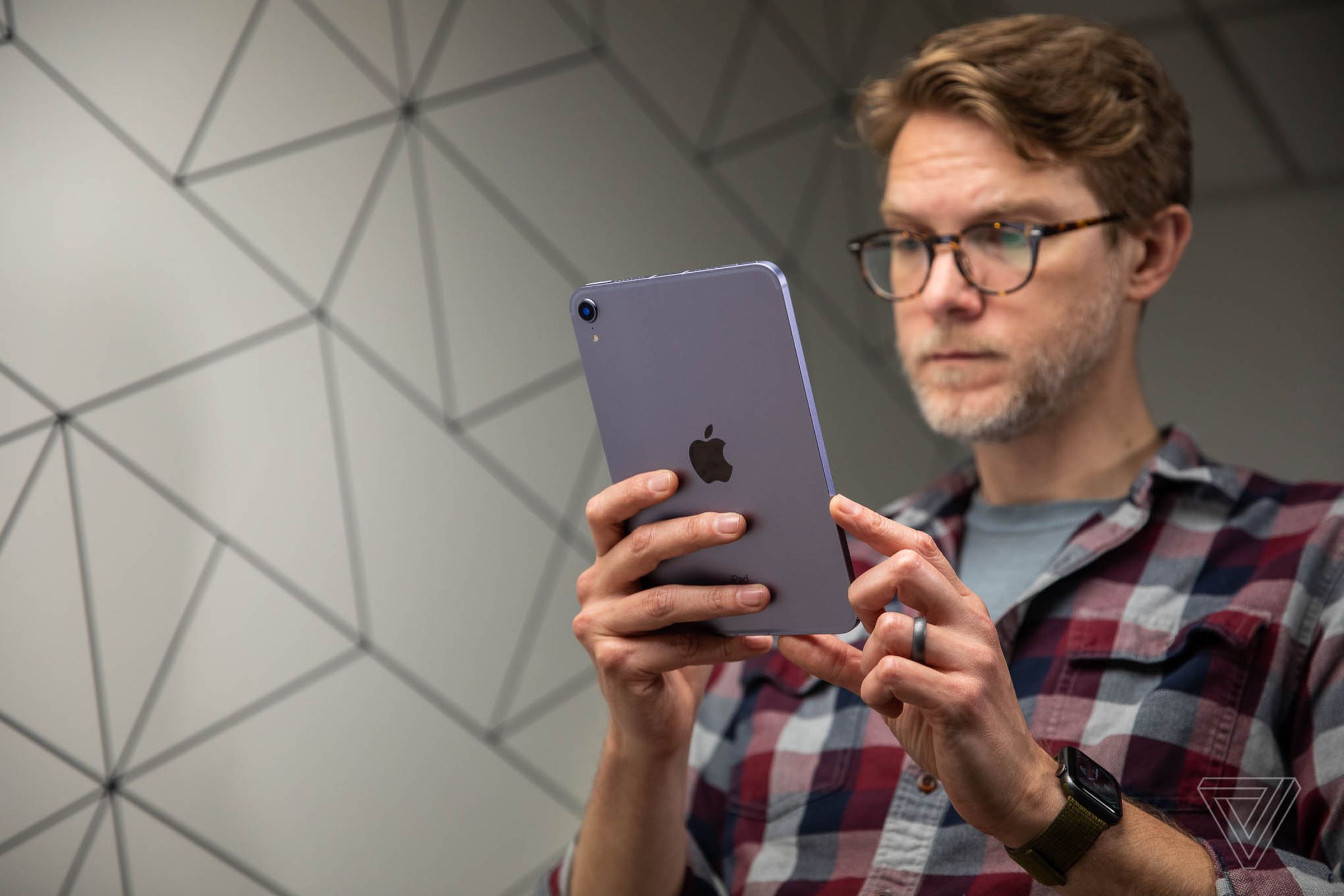 A man holding a purple iPad Mini and looking at the screen