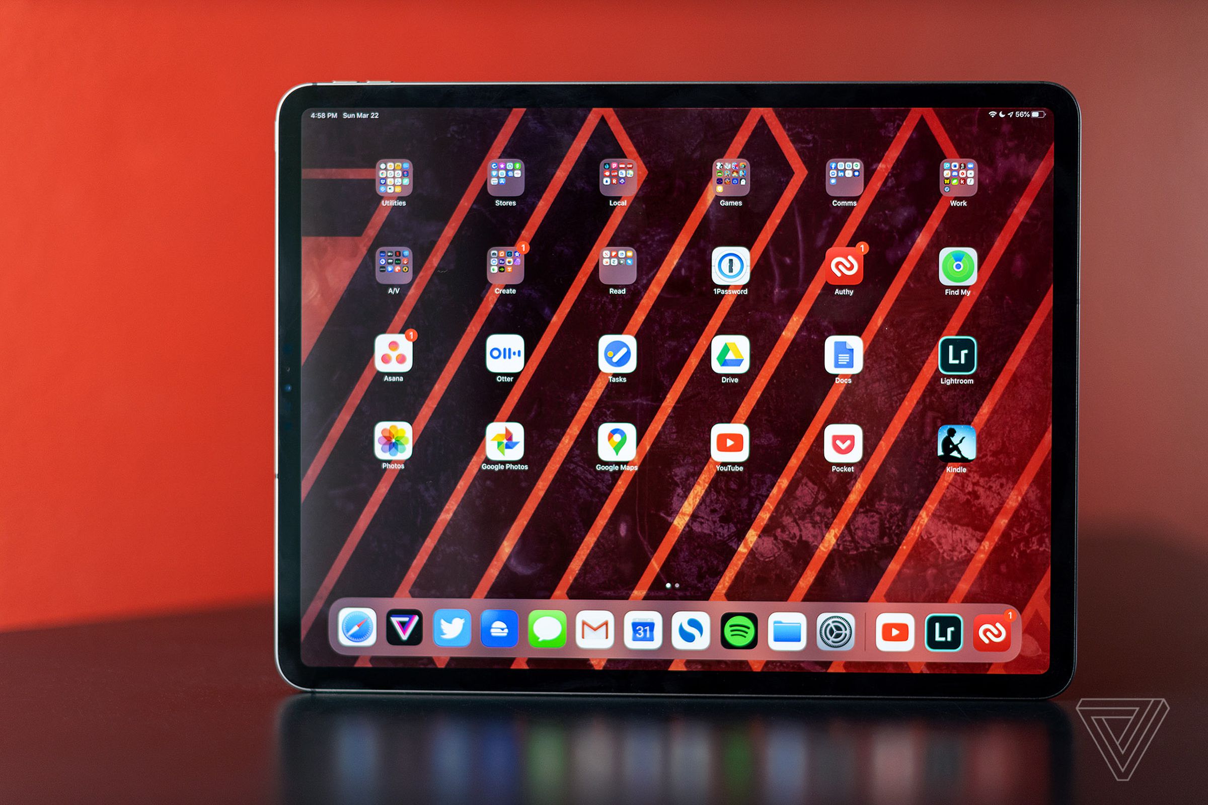 An iPad Pro set on a table in front of a red background