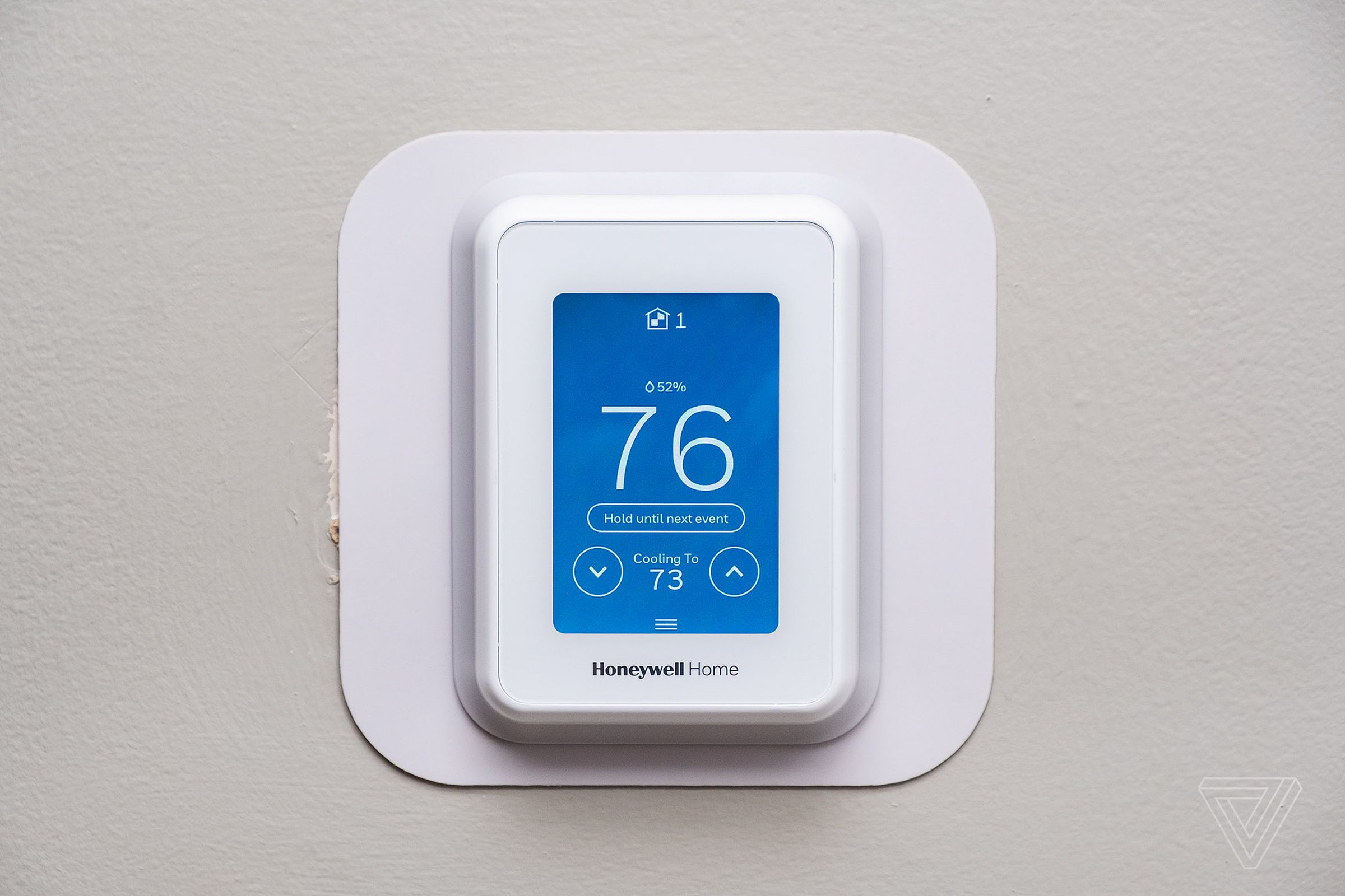A white thermostat on a wall.