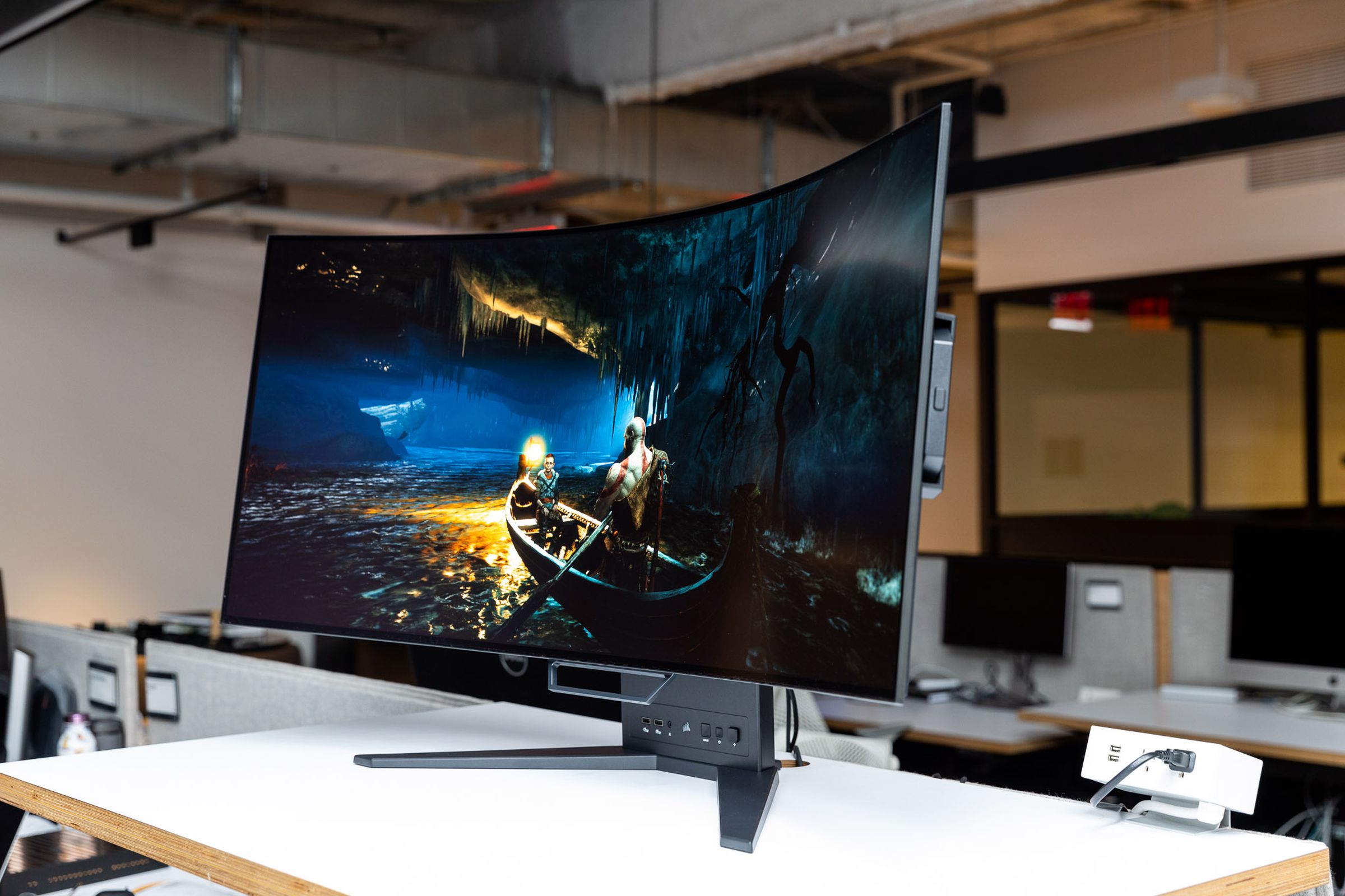 A side view of the Corsair Xeneon Flex OLED gaming monitor, showing a still photo of 2018 God of War on PC.