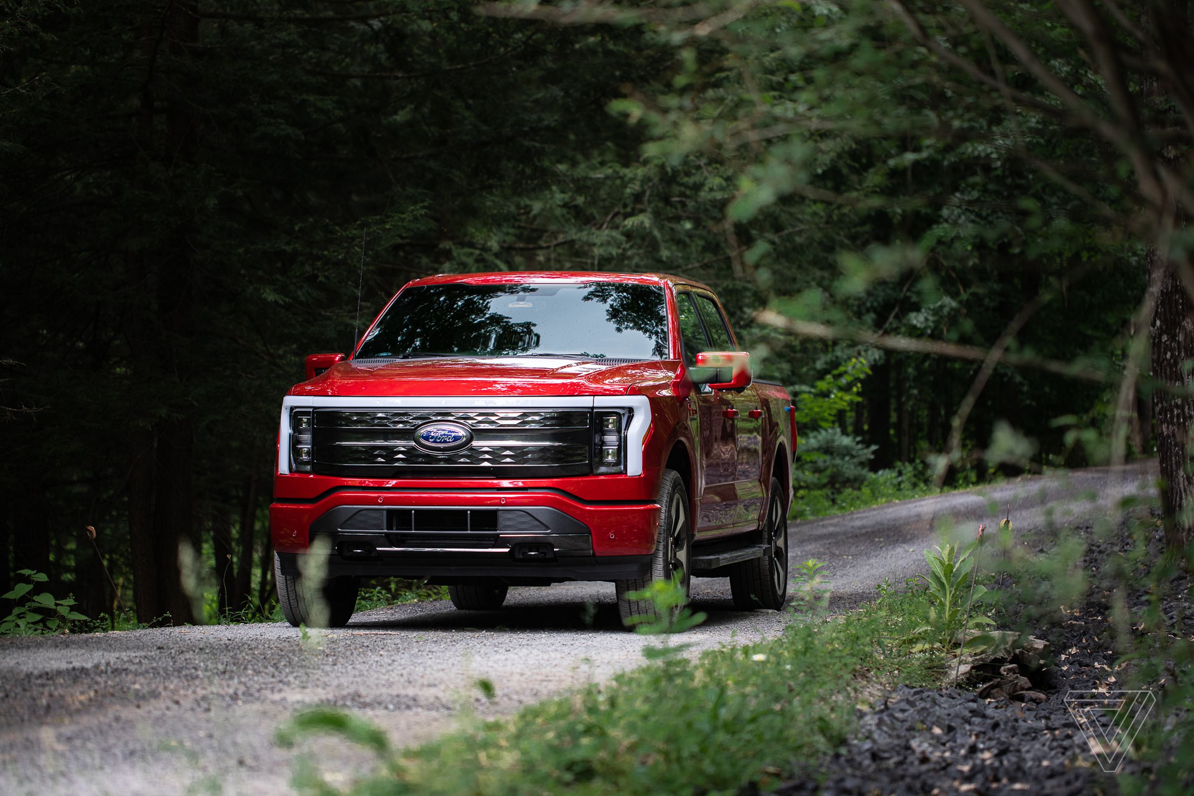 A red Ford F-150 Lightning electric truck on a road