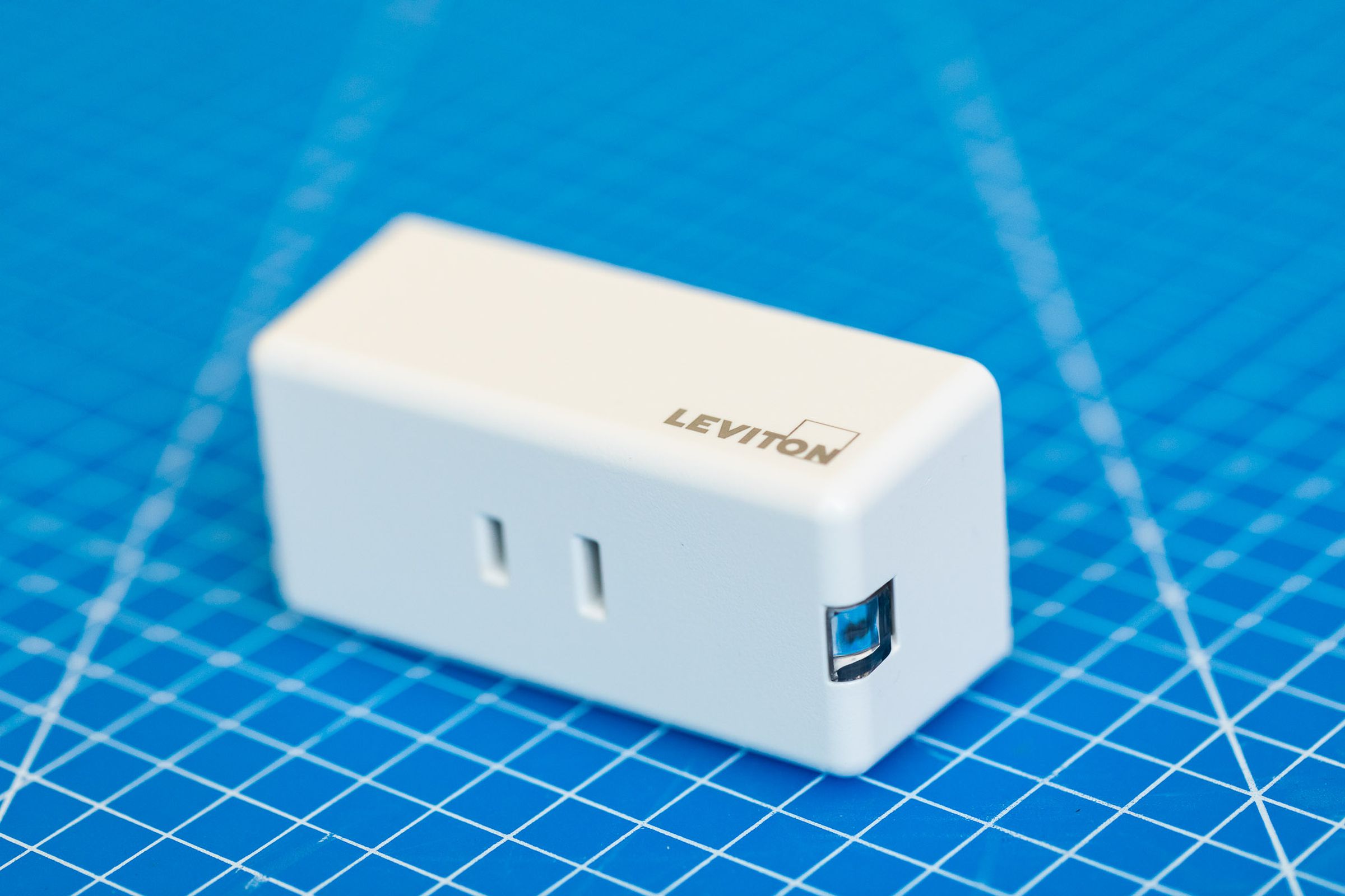 The Leviton smart dimmer, a white rectangular prism with a two-prong US-style AC outlet on the front.