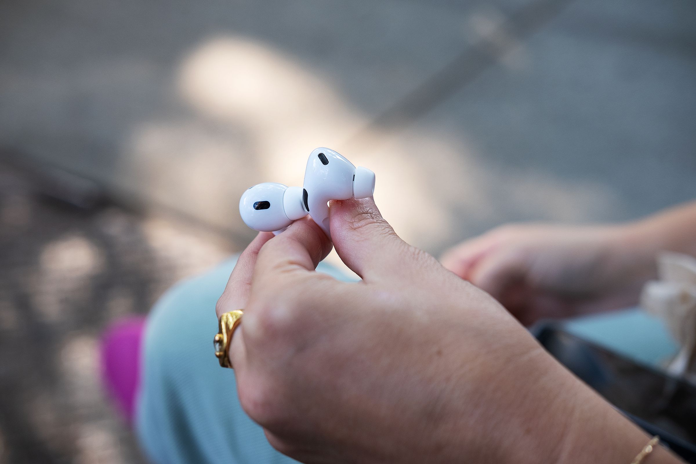 A person holds two AirPods Pro earbuds in their hand.