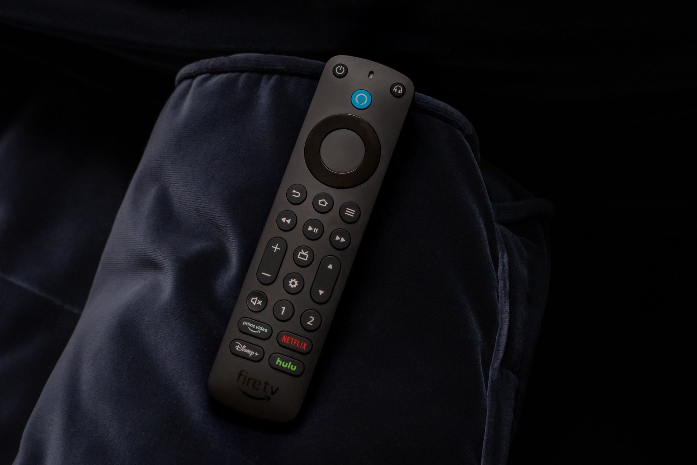 A photo of the Amazon Alexa Voice Remote Pro on a couch arm.