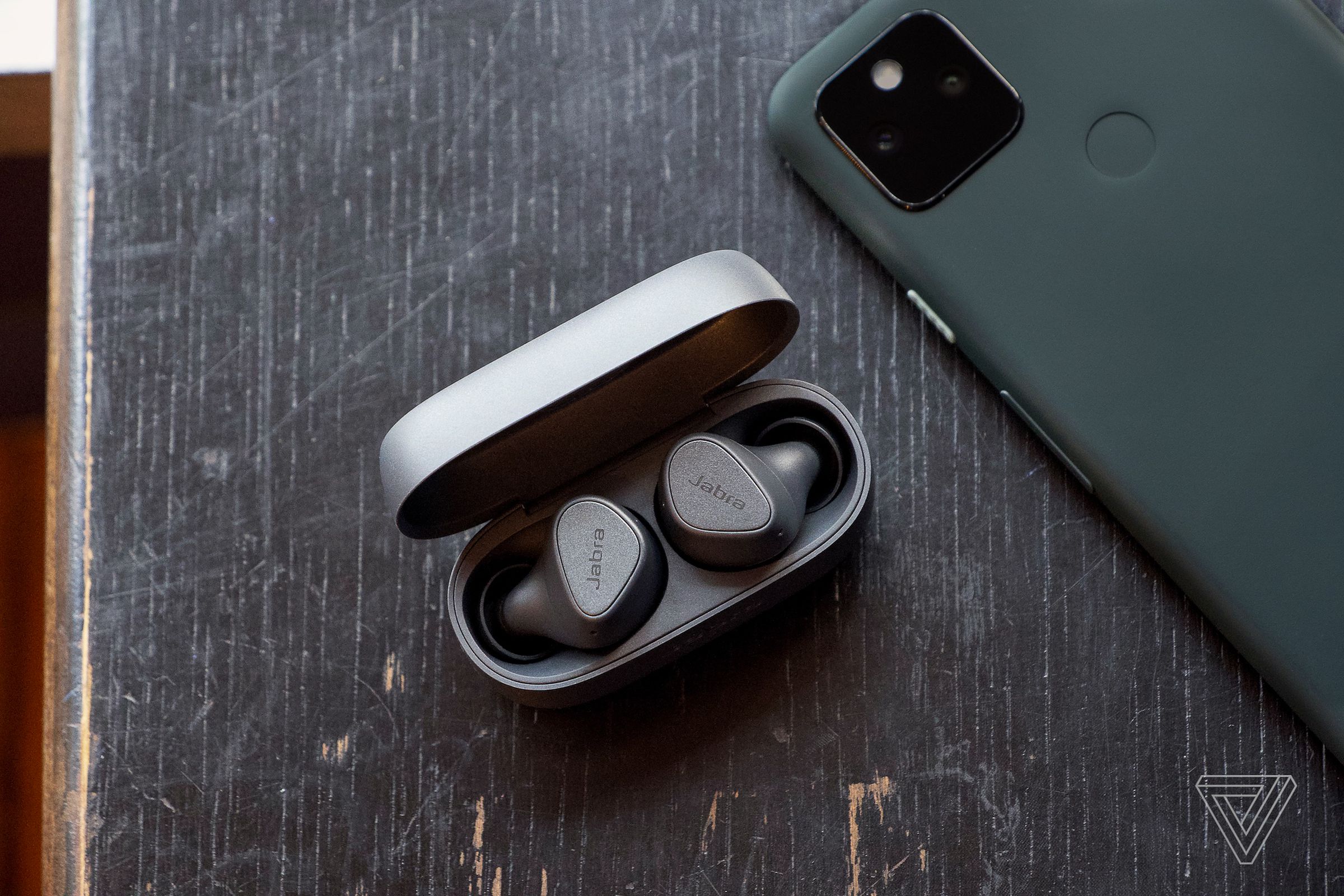 A pair of Jabra’s Elite 3 wireless earbuds sitting on a table near a phone.