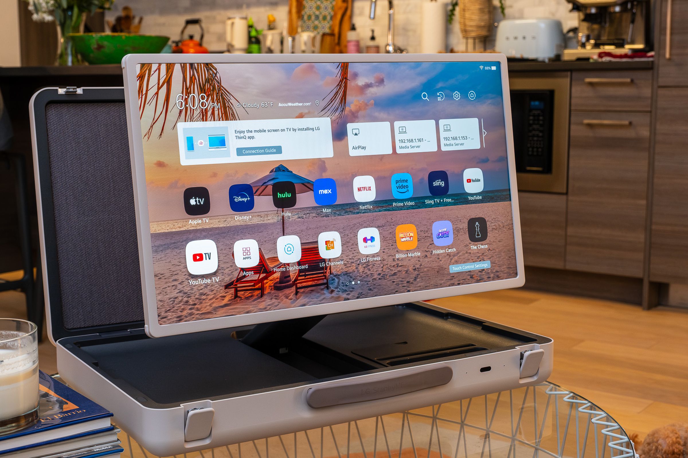 A photo of LG’s StanbyME Go briefcase TV on a living room table with kitchenware in the background.