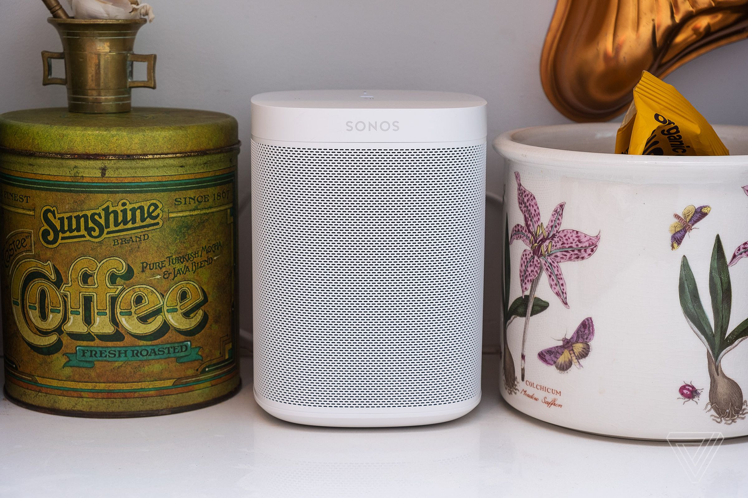 The Sonos Beam sitting on a kitchen counter between a jar and a vase.
