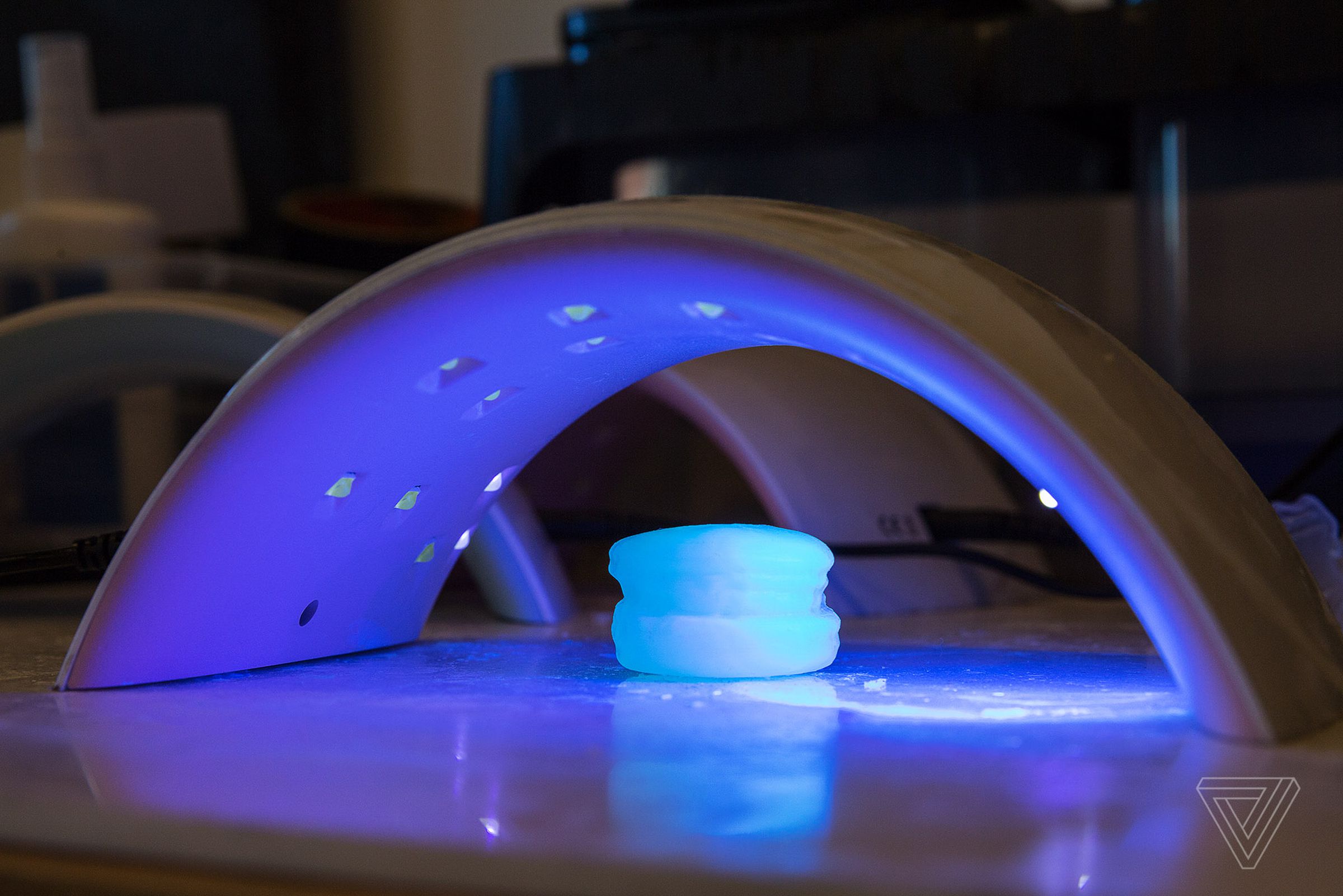 The completed 3D-printed object sits under UV light to harden.