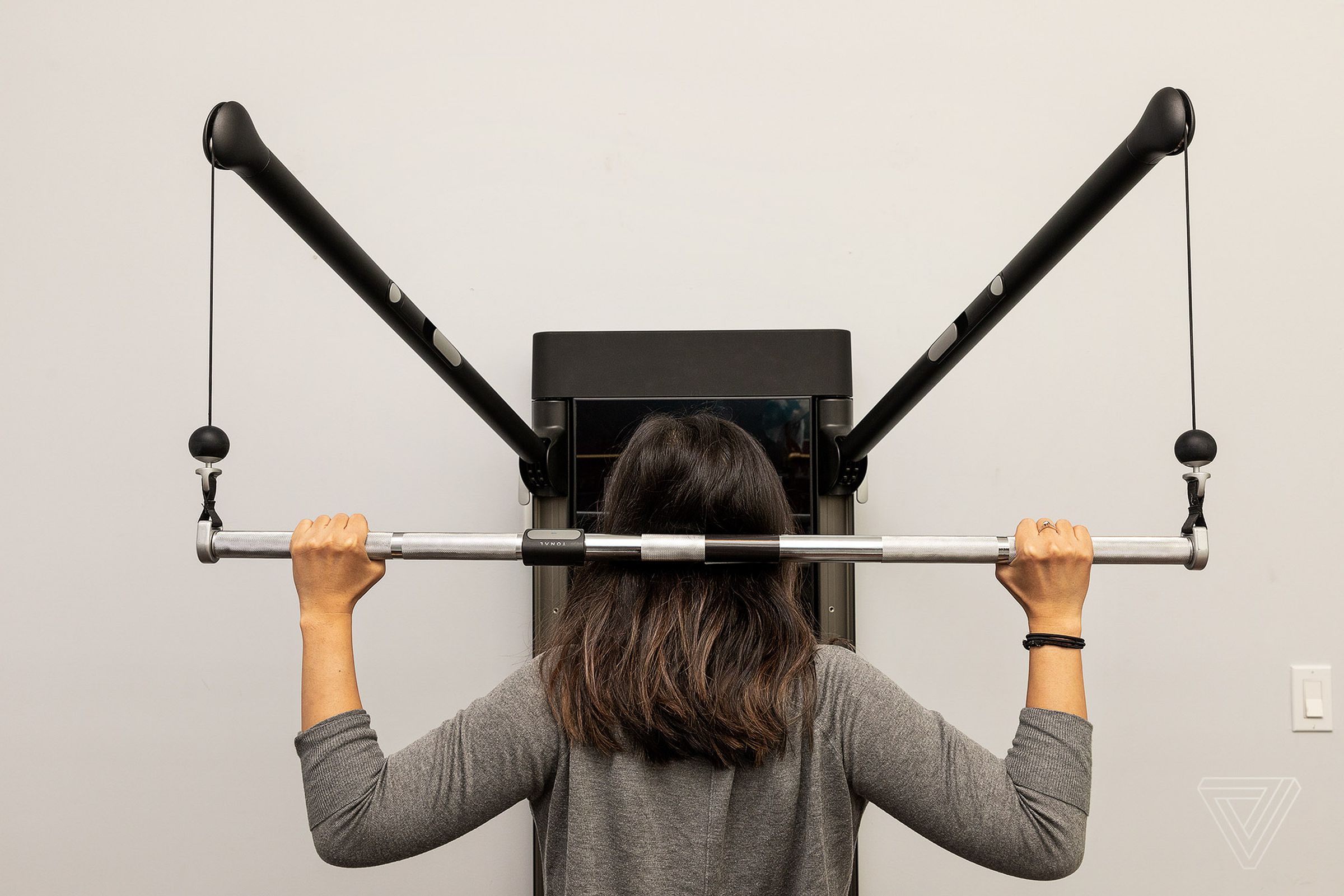 Tonal’s wall-mounted device has interchangeable handles for a variety of exercises.