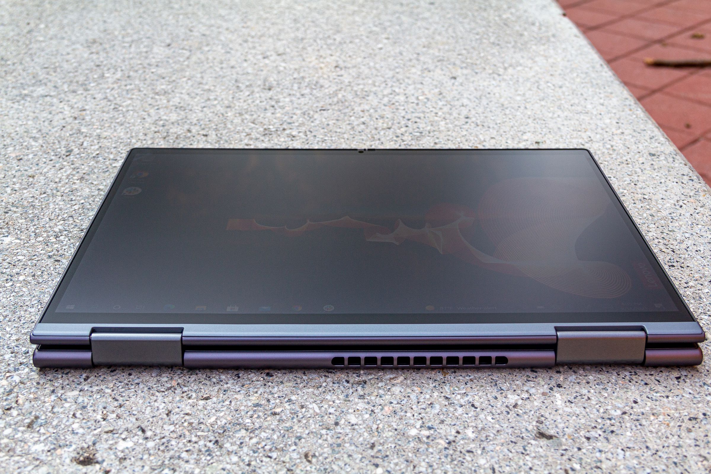 The ThinkPad X1 Yoga in tablet mode, seen from above, on a stone bench.