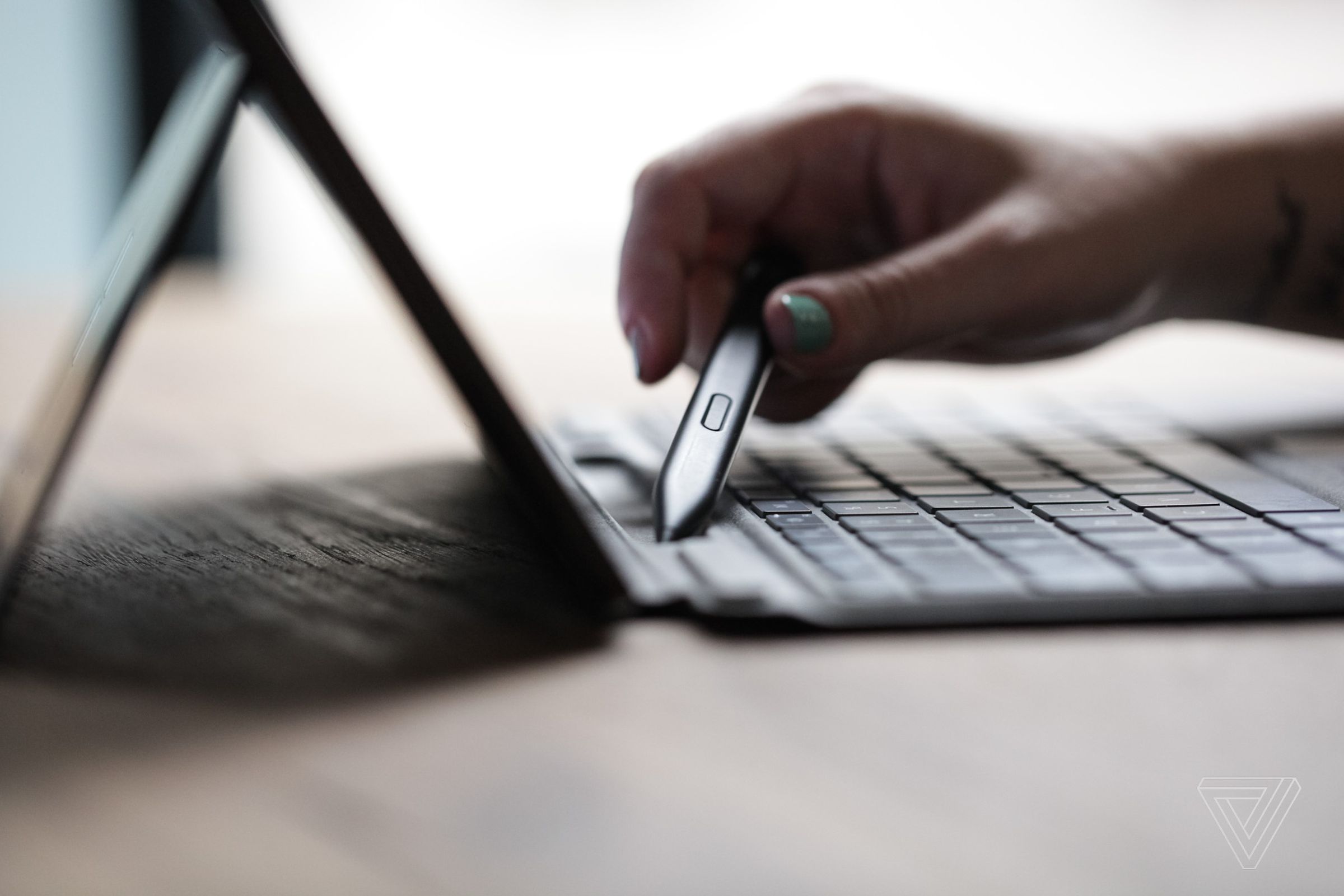 A user removes the Surface Slim Pen 2 from its slot in the Surface Pro 8’s keyboard cover.