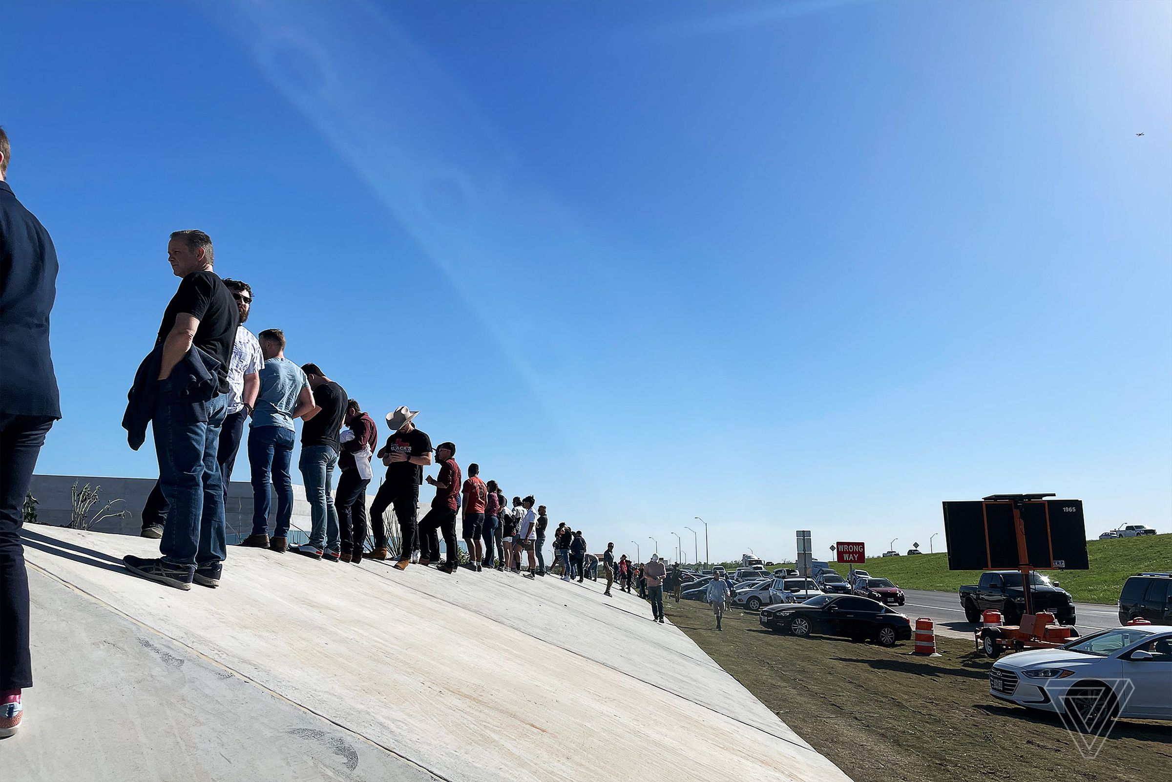 Hopefuls without invites stand on the perimeter of the Gigafactory.