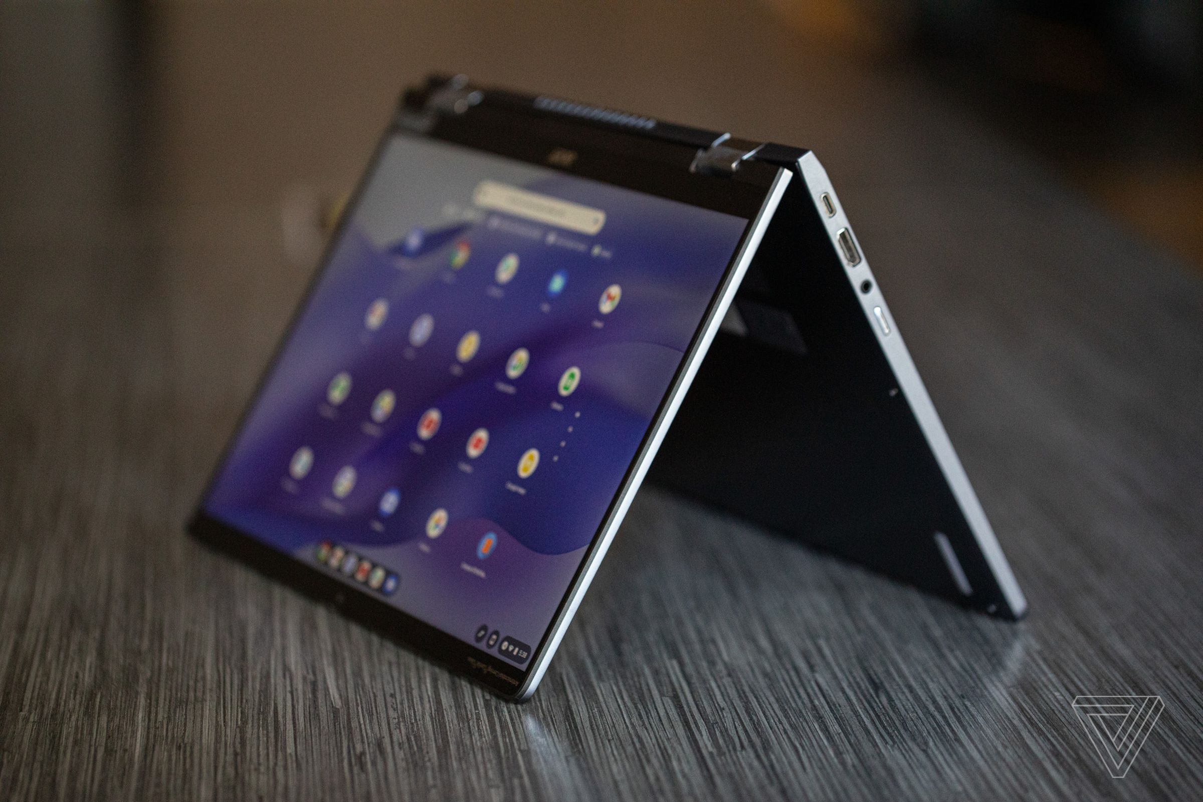 An Acer Chromebook Spin 714, open in stand mode, on a dark wood table.