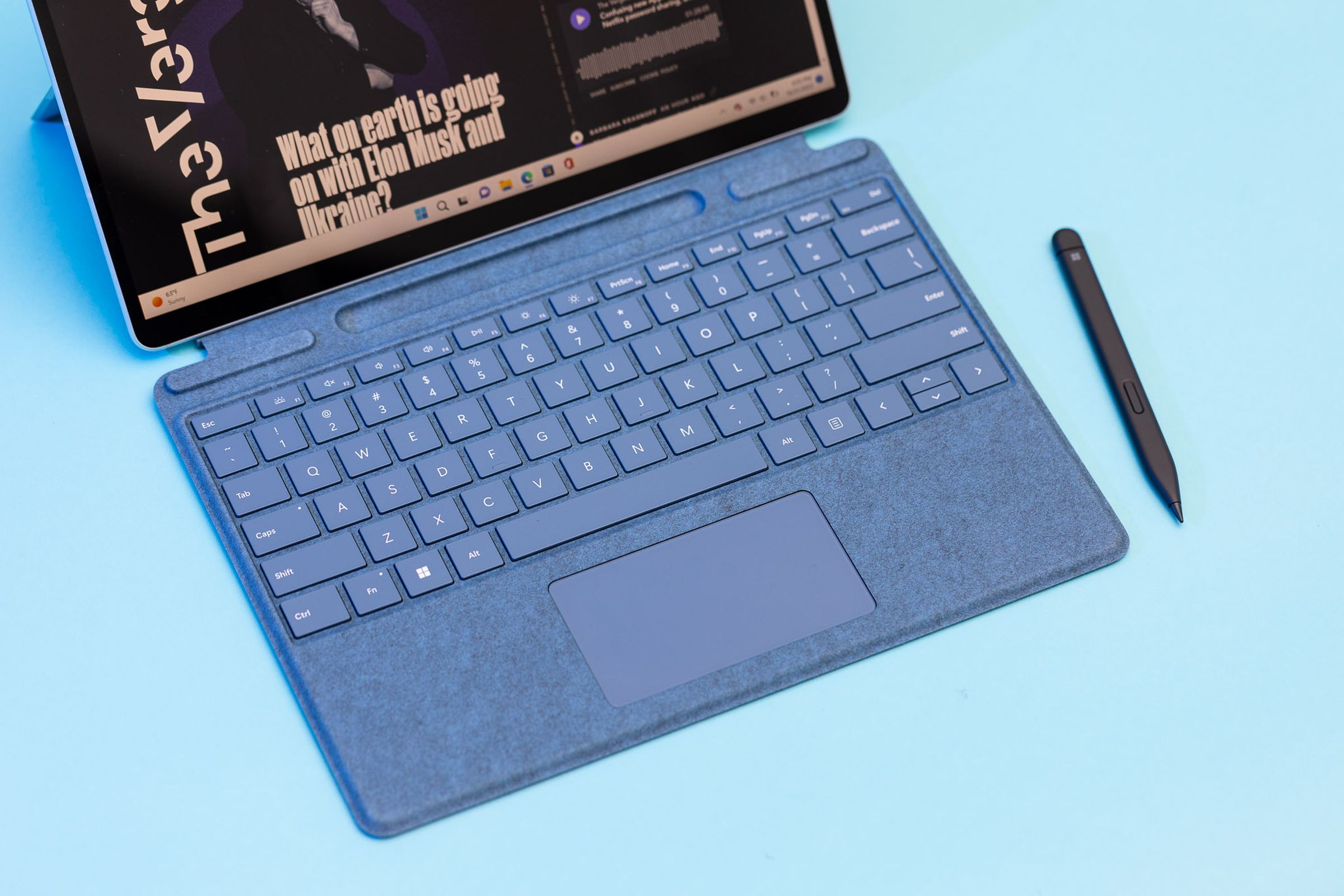 The Surface Pro 9 keyboard deck and stylus seen from above on a blue table cover.