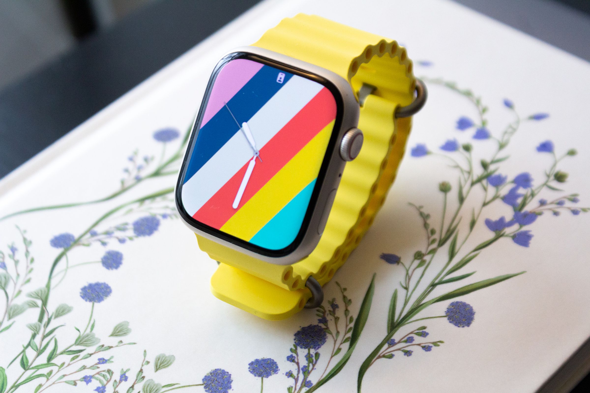 The Apple Watch Series 8 with the yellow Ocean Band on top of a book