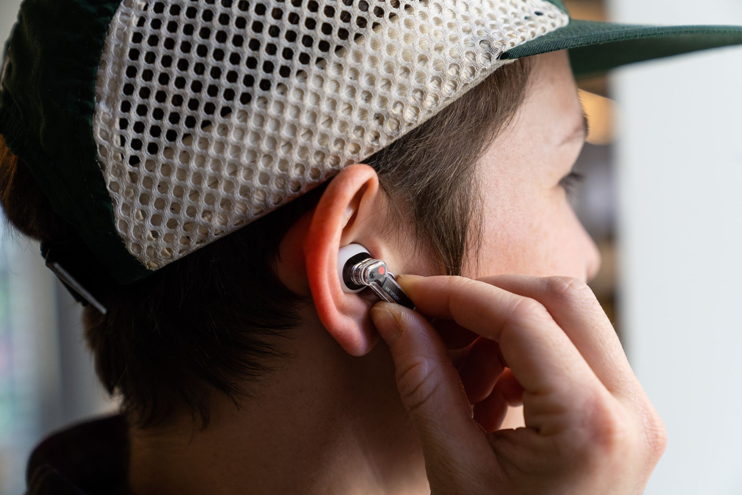 Woman wearing Nothing Ear Stick earbuds, pressing their controls.