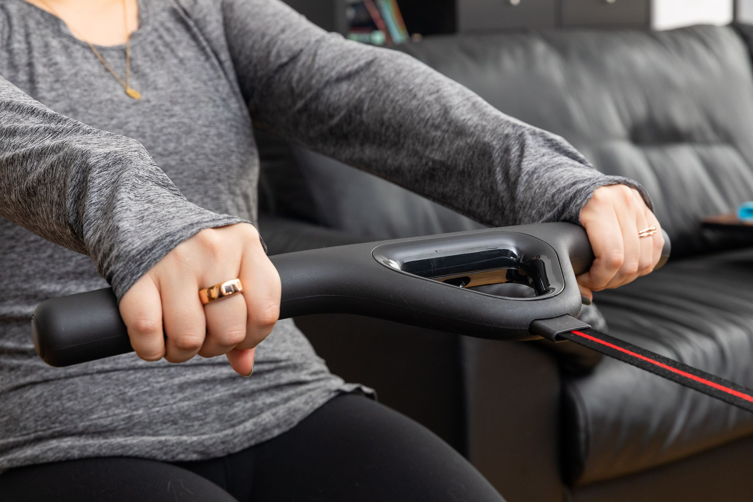 Close-up of woman's hands with three rings while pulling on the Peloton Row's handles