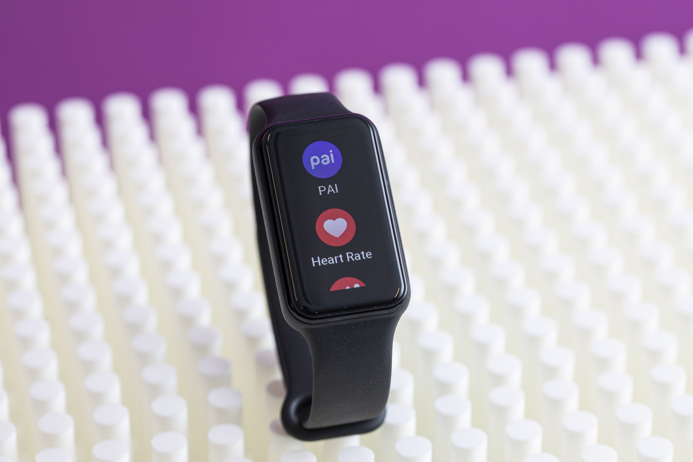 The Amazfit Band 7 on a textured white surface with a purple background.