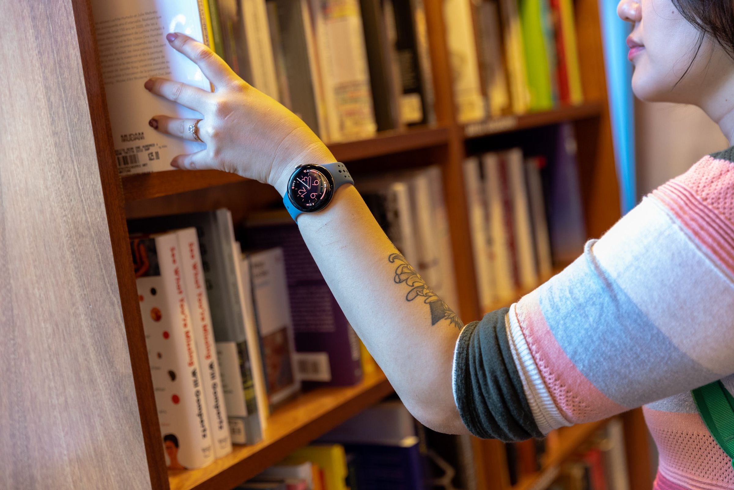 Person wearing Pixel Watch 2 while pulling book off shelf