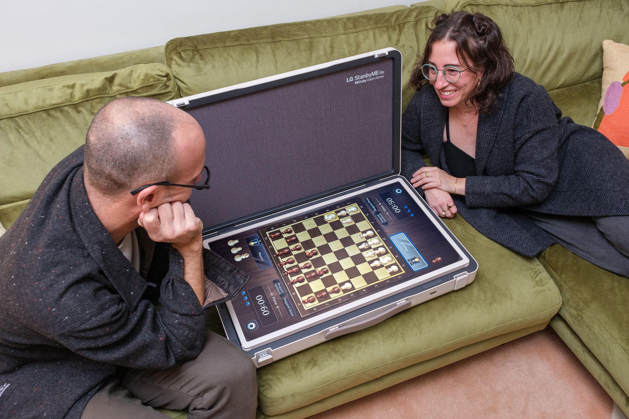 A photo of a couple playing touchscreen chess on LG’s StanbyME Go briefcase TV.