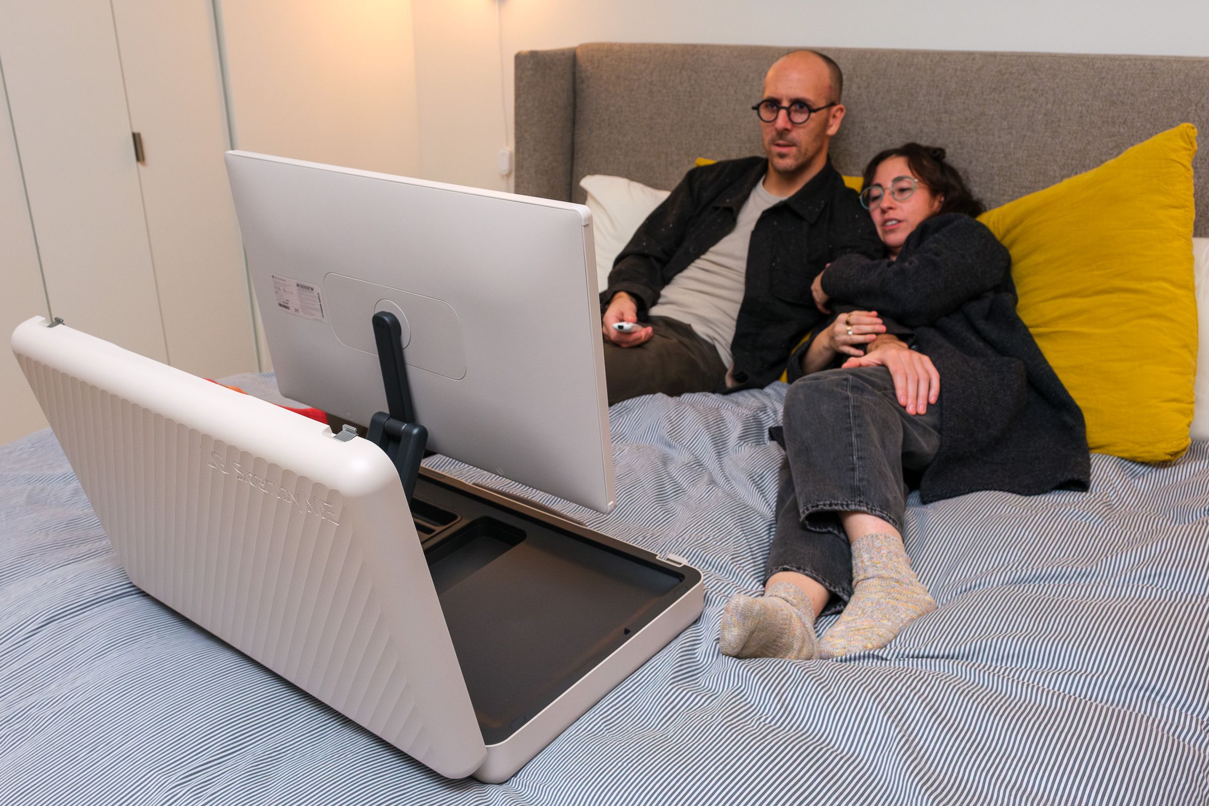 A photo of a couple laying in bed watching LG’s StanbyME Go briefcase TV.