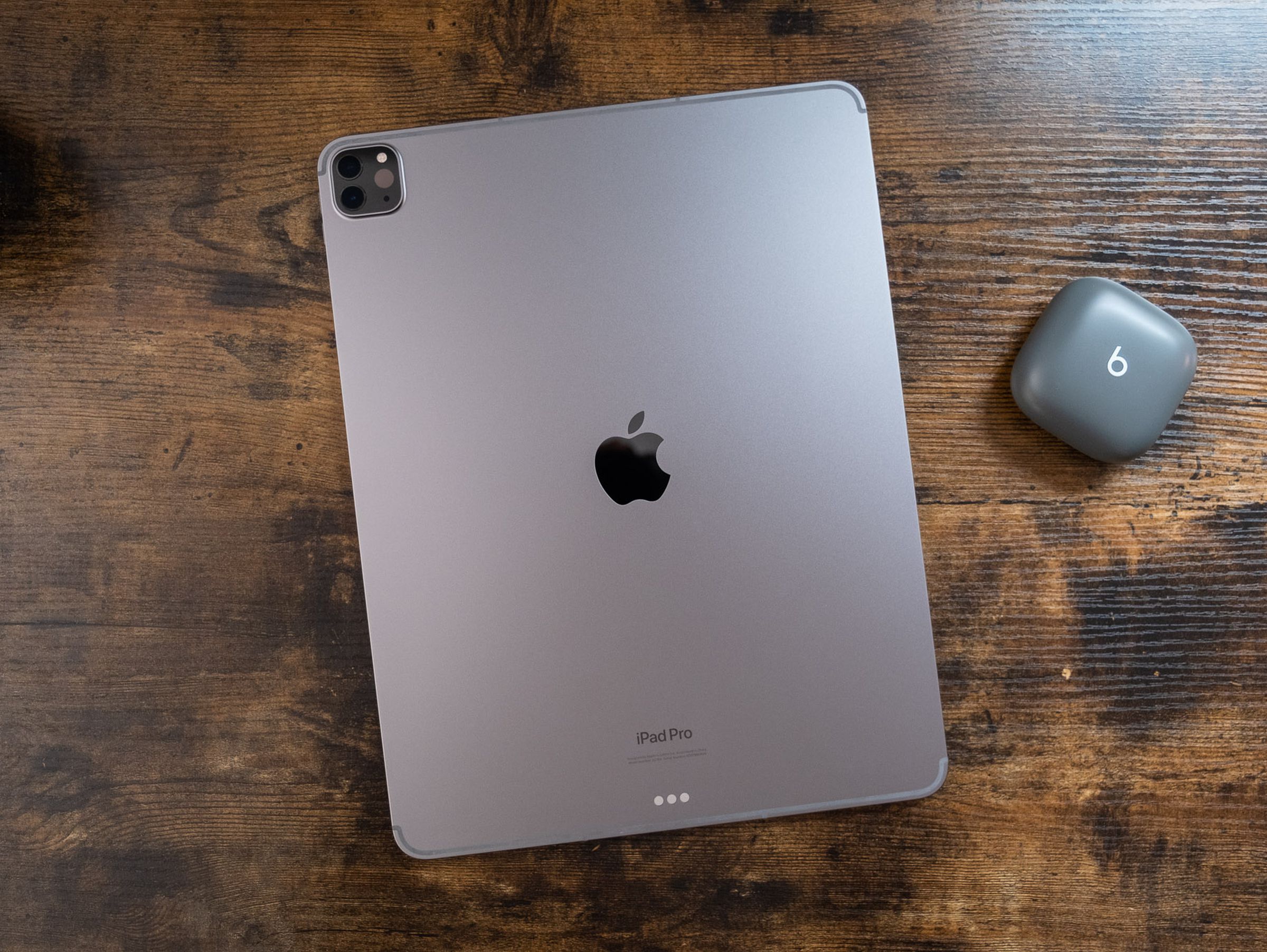 A 12.9-inch space gray iPad Pro face down on a wooden table, viewed from the top down.