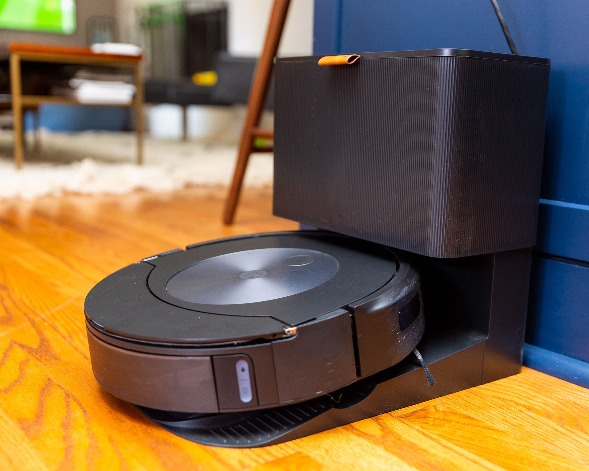 A Roomba vacuum on its docking station in an open plan kitchen living room.
